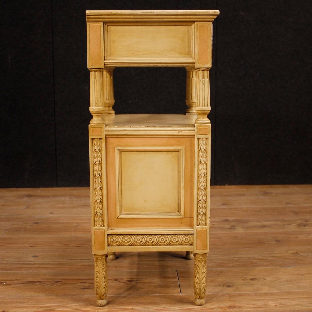 Italian side table from 20th century. Furniture in carved, lacquered and painted wood in neoclassical style. nightstand with a drawer, a door with a fall-front and two shelves. Side table covered internally with pink fabric (see photo), in good