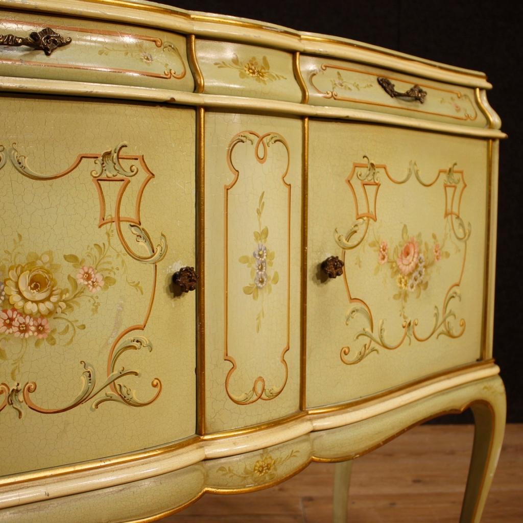 Venetian sideboard from 20th century. Furniture in lacquered, gilded and hand painted wood with floral decorations. Sideboard with two doors and two drawers of excellent proportion and service. Top in lacquered and painted wood. In good condition