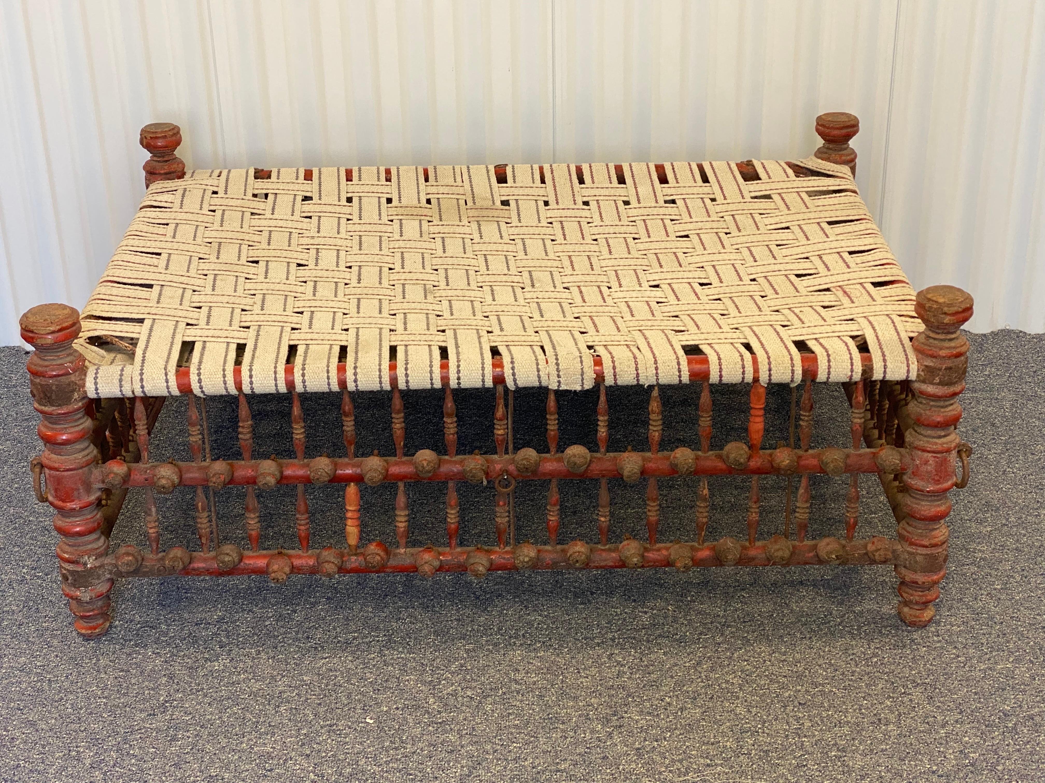 20th century Indian Red Painted Wooden Ball & Stick Ottoman
A rustic red painted wood frame with upholstery tape woven to create a top. A piece of glass could be used instead of the woven tape or a thin cushion could be fabricated to go on top.