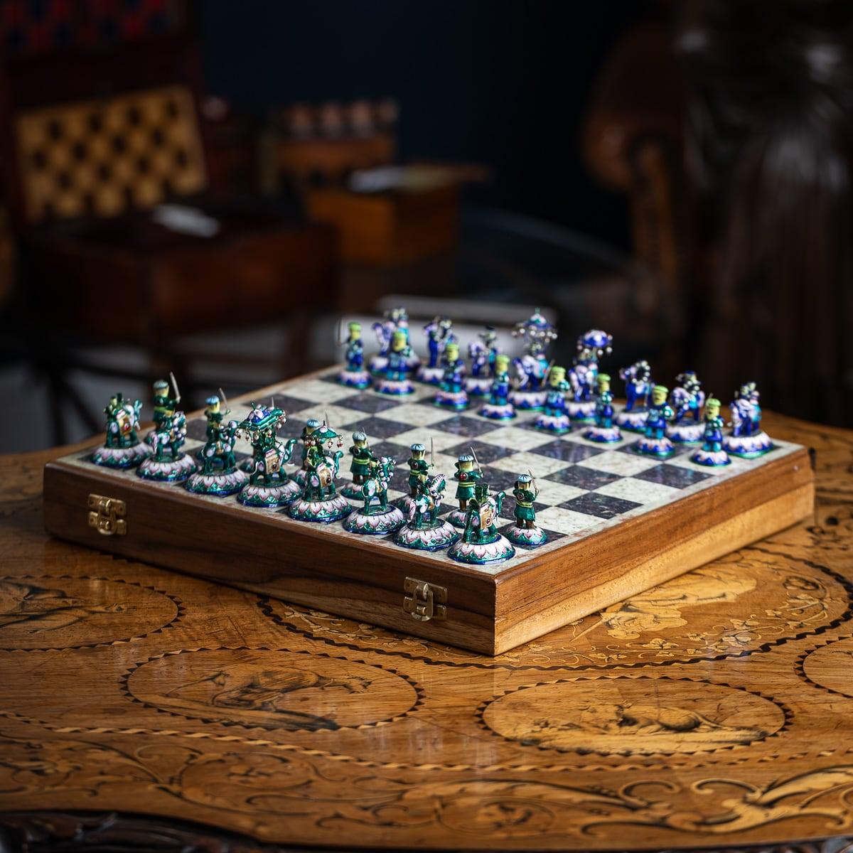 Set di scacchi indiano in argento massiccio e smalto dipinto a mano della metà del XX secolo, completo di 32 pezzi. Presentato in una scatola di legno con una scacchiera intarsiata in marmo. Un lato è caratterizzato da uno smalto blu, l'altro verde.
