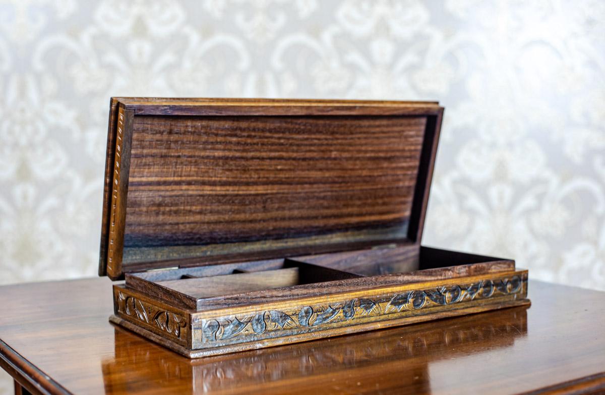 We present you a big coffret in the shape of a book.
It is from before the year 1939.
This item is made of exotic wood, and the outer surface is covered with relief decoration.
Its intended use is to store writing instruments.
Inside, there is a