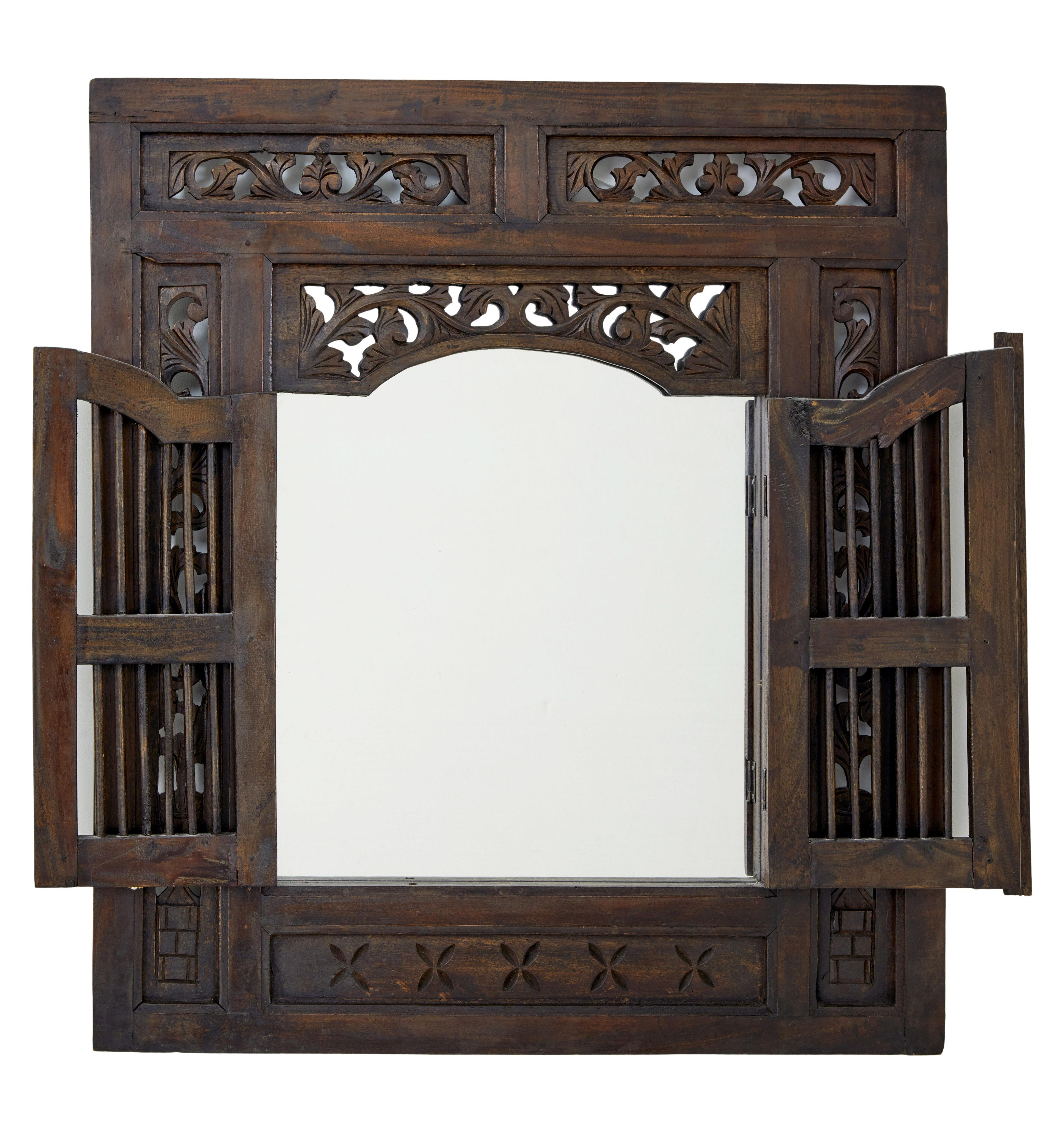 Decorative mirror made from oriental hardwood.

Central carved pierced border, with a central double door opening which reveals the mirror.

Minor surface marks.