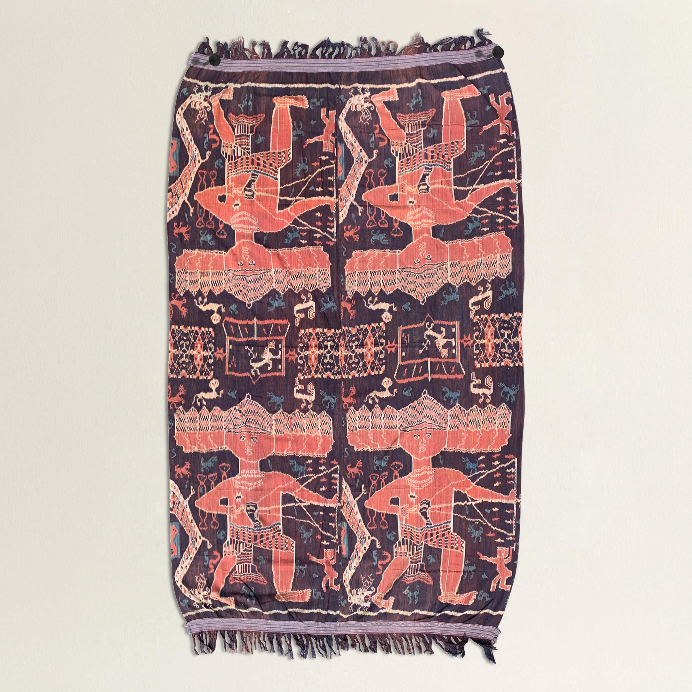 An incredible 20th century Indonesian hand-loomed ikat textile from the island of Sumba and depicting a hunting scene with several large multi-headed figures carrying bows and arrows, amidst a field with lions, birds, and serpents, all woven in