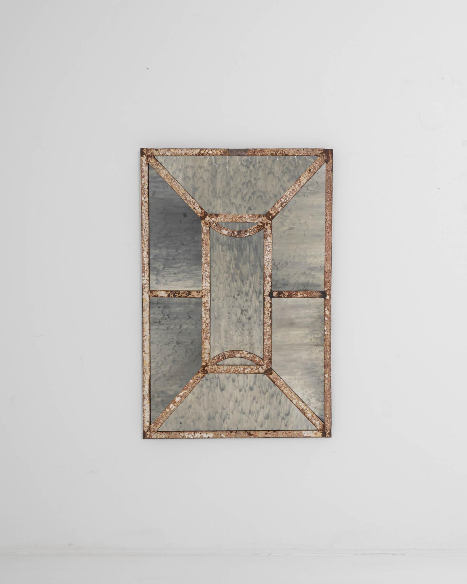 An elegant geometric design and an enigmatic patina give this vintage mirror an intriguing sculptural quality. Made in France in the 20th Century, the metal mullions which traverse the glass create a pattern of angular lines and streamlined curves,