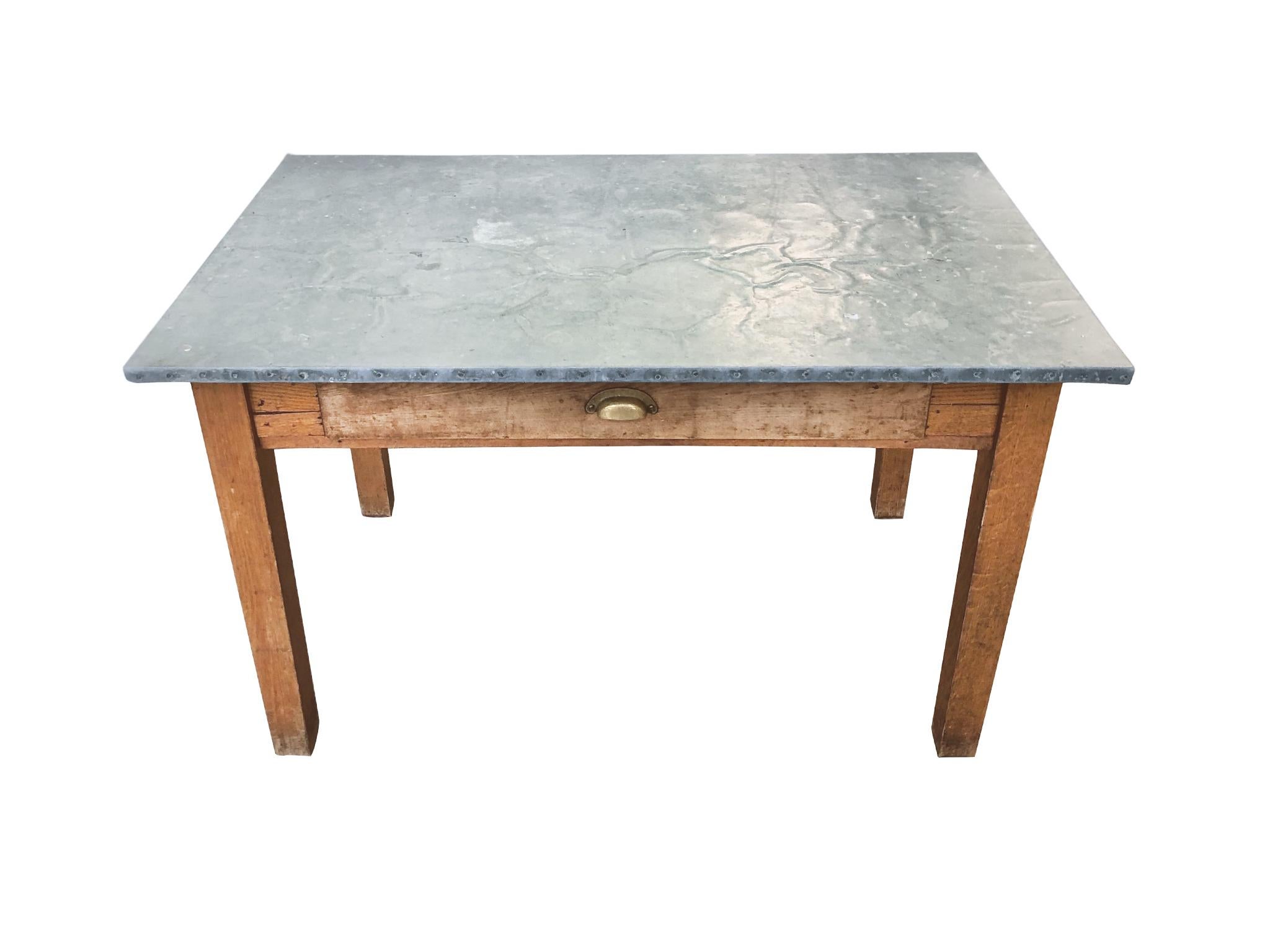 A 20th century modestly sized table that can be used as a dining table, work table, or desk. Handmade, 1930s-1940s. The table is comprised of a zinc-wrapped top and pine base with a single drawer. The zinc and pine have aged beautifully. They've