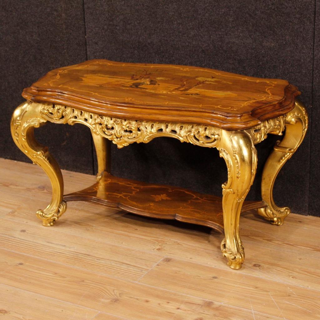 Italian coffee table from 20th century. Furniture in richly carved, gilded and inlaid in various woods of beautiful lines and pleasant decor. Furniture with two inlaid support tops, the upper one adorned with an 18th-century hunting scene. Coffee