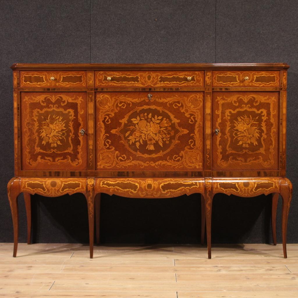 Gran mueble bar italiano de mediados del siglo XX. Aparador de patas altas ricamente incrustado con decoraciones florales de gran placer. Mueble equipado con seis cajones, dos puertas laterales y una central abatible que ofrece en su interior cuatro