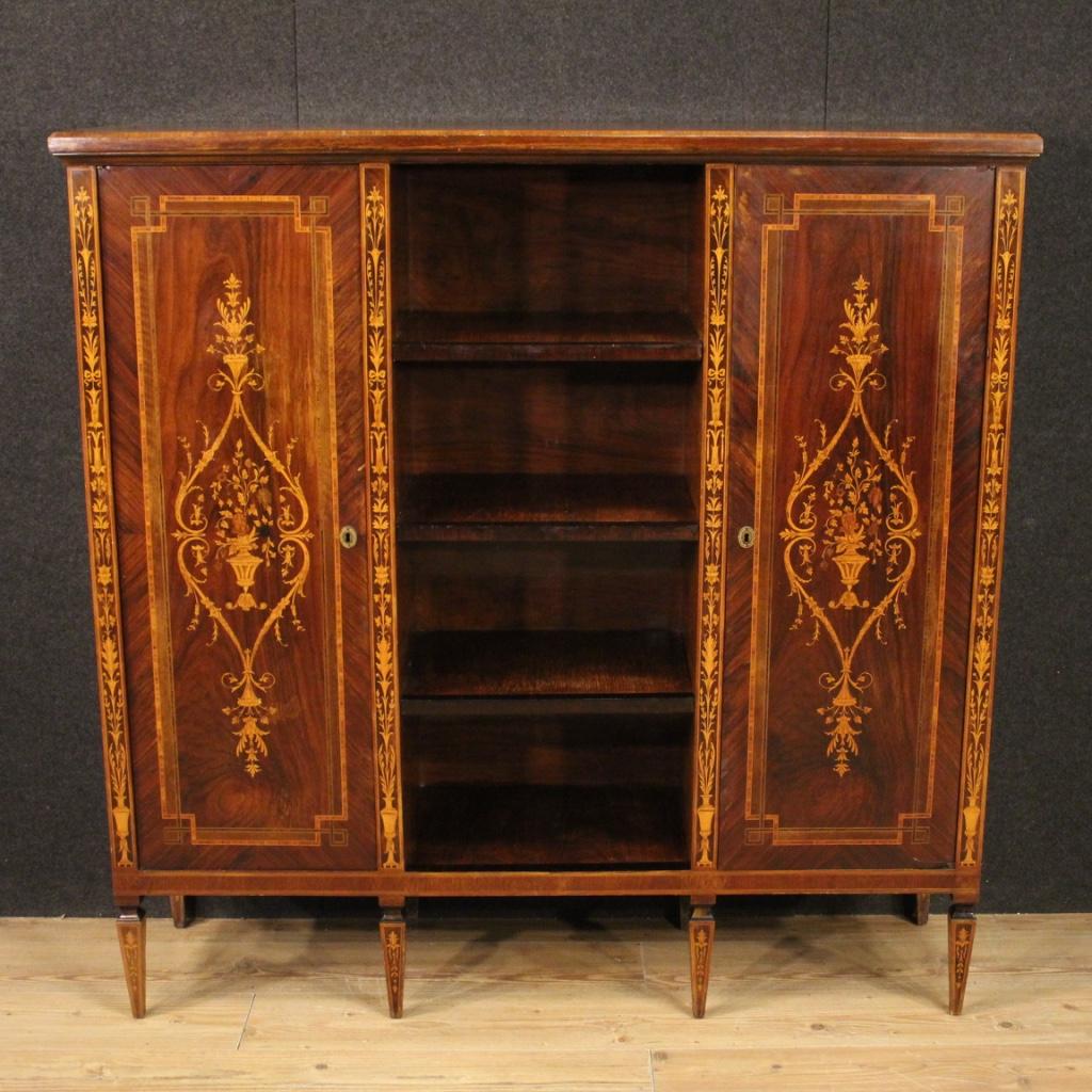 Italian bookcase from 20th century. Furniture built in a single non-divisible body, in Louis XVI style, pleasantly inlaid in walnut, palisander, rosewood, maple and fruitwood. Bookcase unit with two side doors and open shelves in the central part of