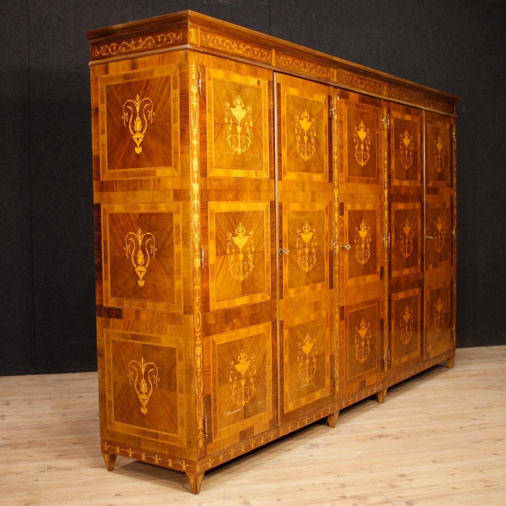 20th century Italian wardrobe. Furniture in Louis XVI style richly inlaid in walnut, palisander, rosewood, burl, maple and fruitwood. Wardrobe with 5 doors of exceptional capacity and service complete with a drawer, a hatbox covered in cane and