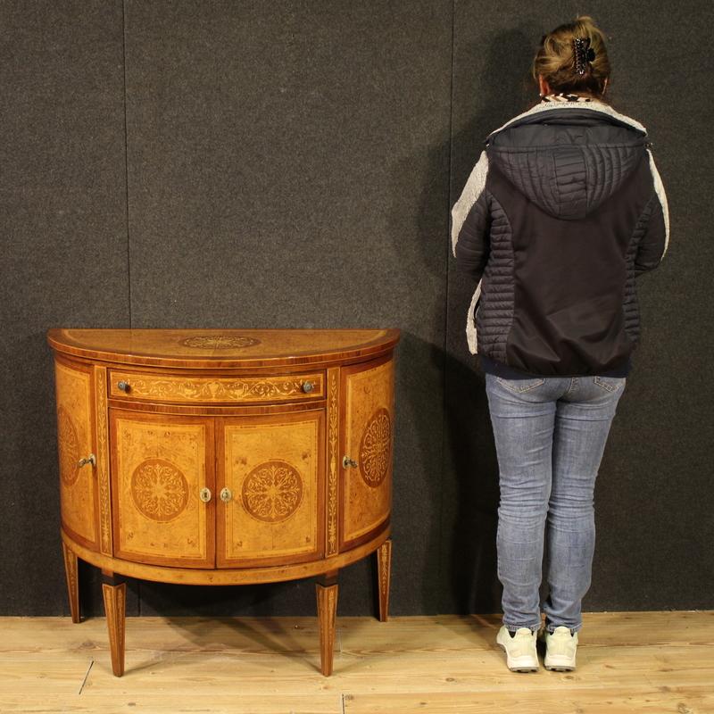 Italian sideboard from the second half of the 20th century. This Louis XVI-style furniture is finely inlaid with walnut, rosewood, burl, maple, and fruitwood. The half-moon sideboard features four doors and a drawer beneath the carved wooden