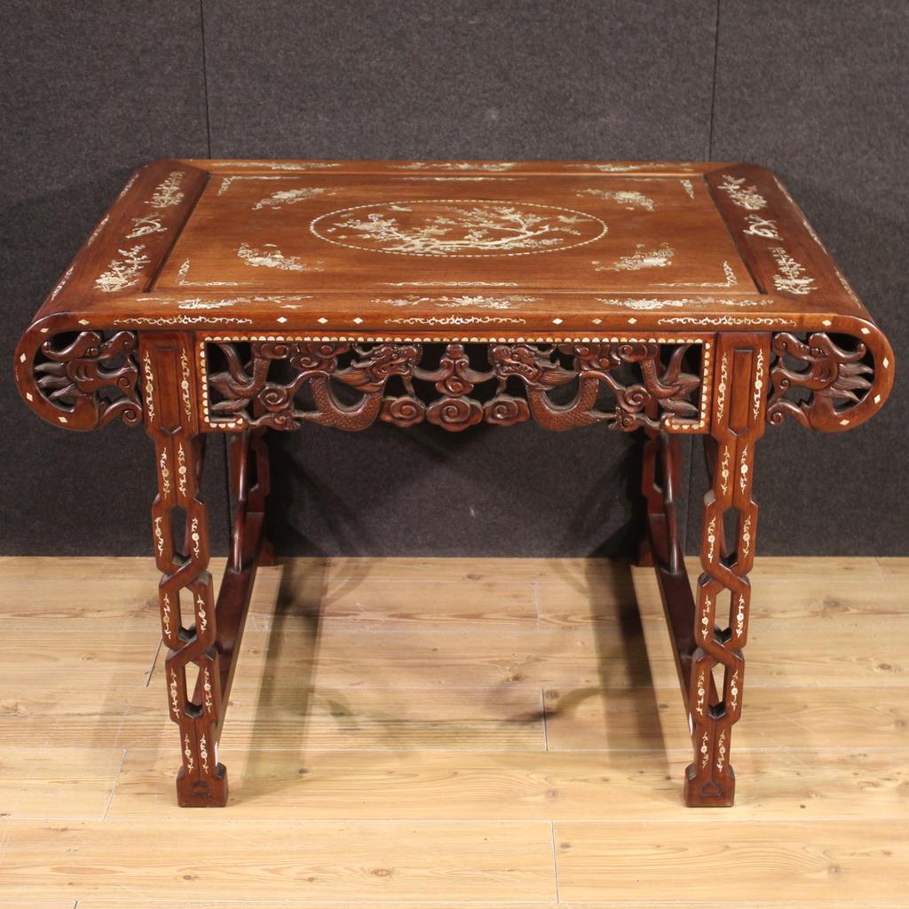 Splendid oriental table from the 20th century. Furniture richly inlaid in fake mother-of-pearl with excellent quality floral and animal motifs. Console in exotic wood carved with depictions of dragons in the clouds, with great charm. Table supported