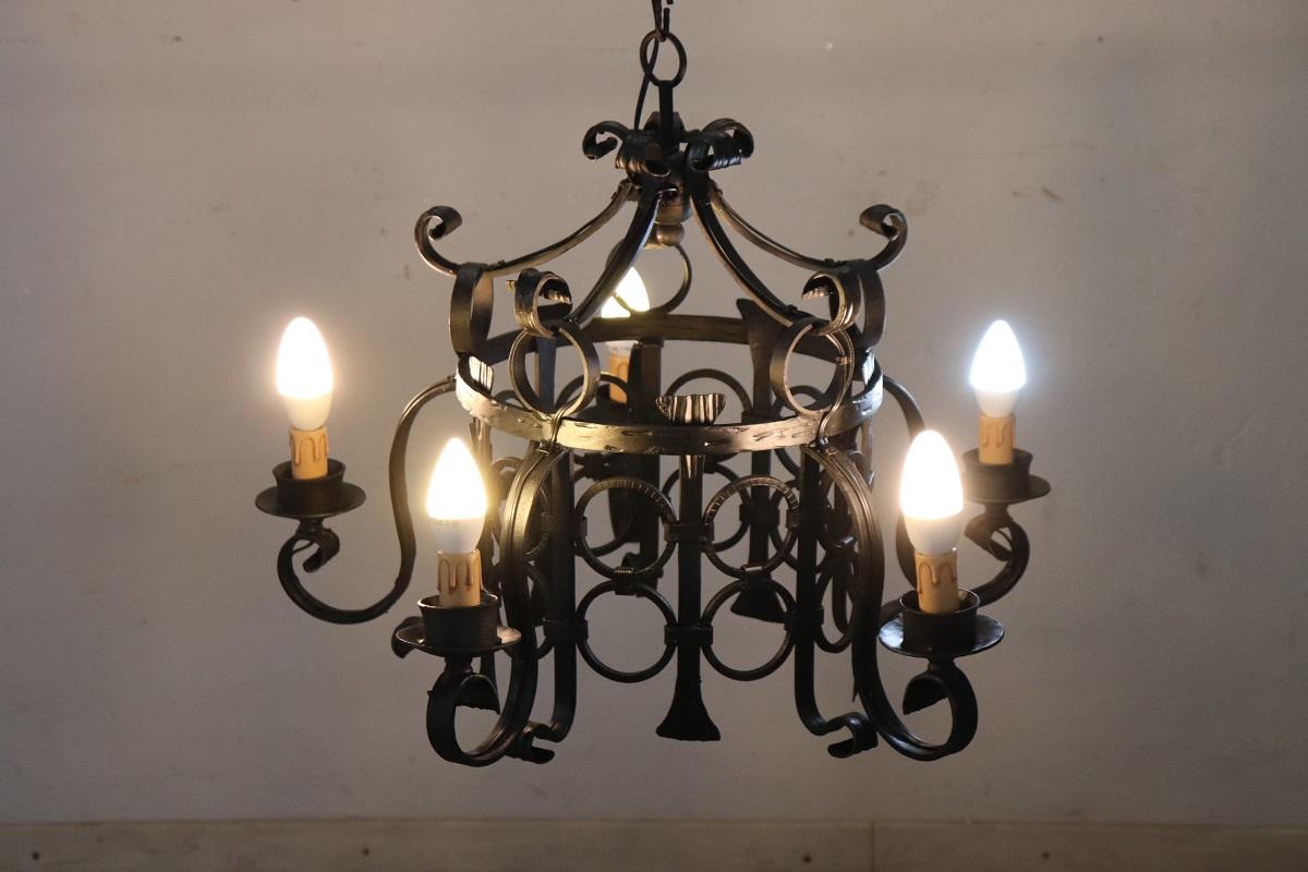Questo squisito lampadario in ferro nero, risalente alla prima metà del XX secolo, è un pezzo sorprendente caratterizzato da riccioli e volute intricate. Il suo design evoca un senso di eleganza senza tempo e di robusta maestria, tipica dell'epoca.