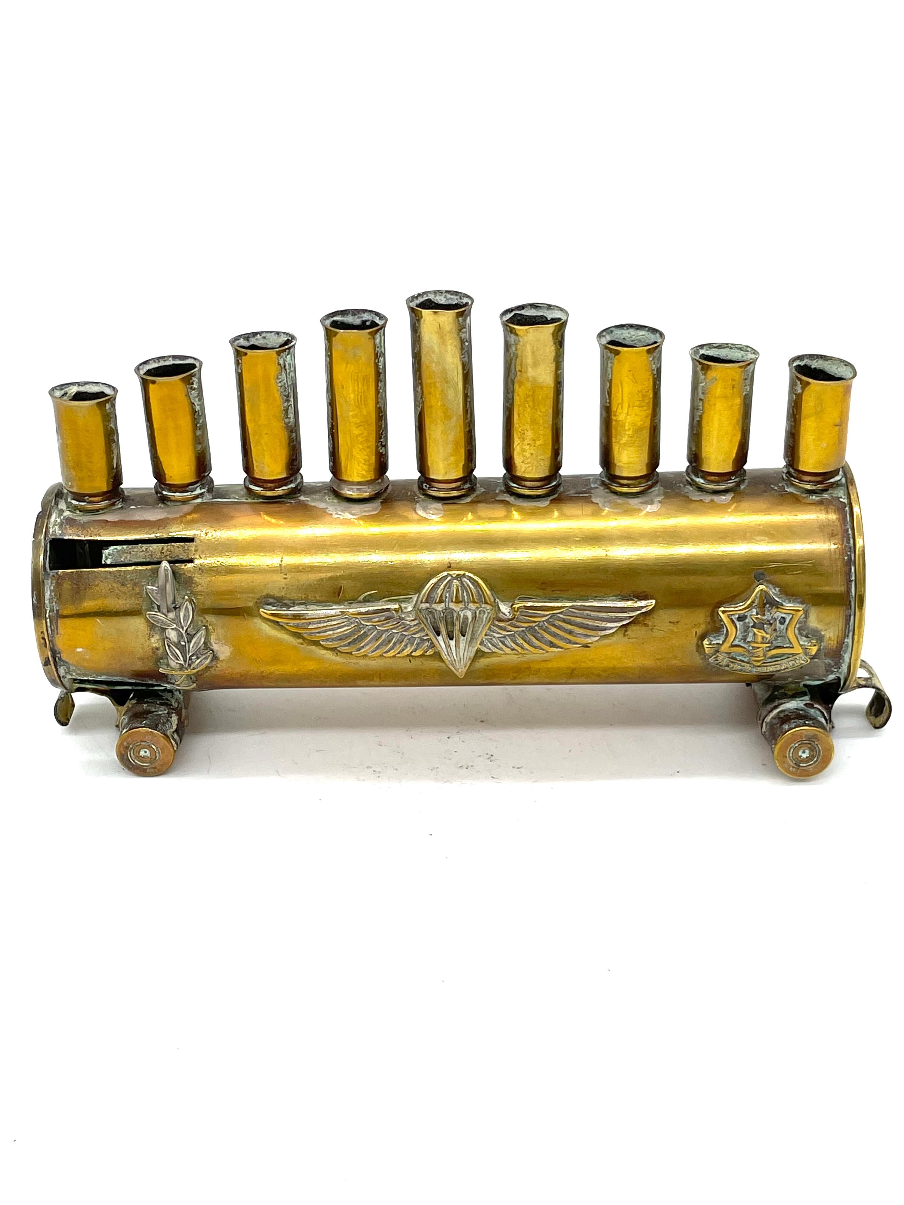 A brass Hanukkah lamp made by Israeli Defense soldiers features nine bullet and shell cartridges in the form of candleholders. The bullet cartridges soldered onto a 40-mm shell cartridge, itself supported on two additional bullet cartridges.