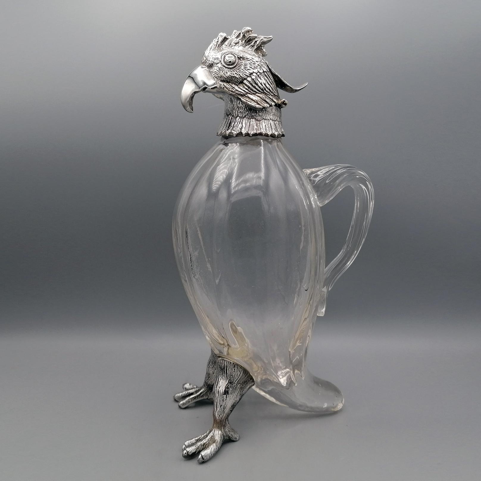 Jug with the shape of a parrot. The body is in crystal while the head is the legs are in silver.
The head of the parrot is fixed to the neck with a hinge. This is to allow the liquid to be added to the jug.
Solid silver 670 grams.