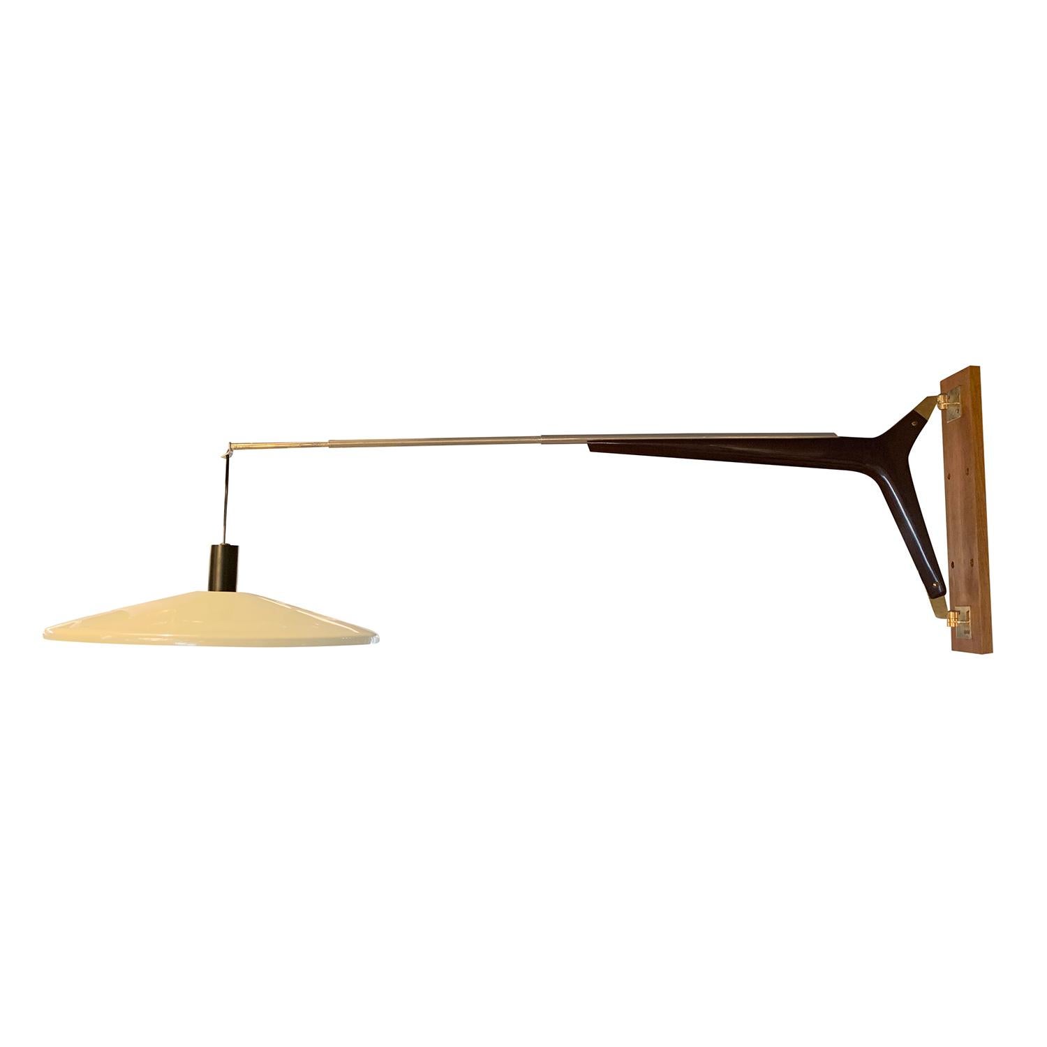 A yellow, vintage Mid-Century modern Italian extendible reading wall lamp made of hand carved Walnut, metal and brass, produced by Stilnovo in good condition. The light yellow lacquered aluminum shade is supported by a brass arm, ideally for
