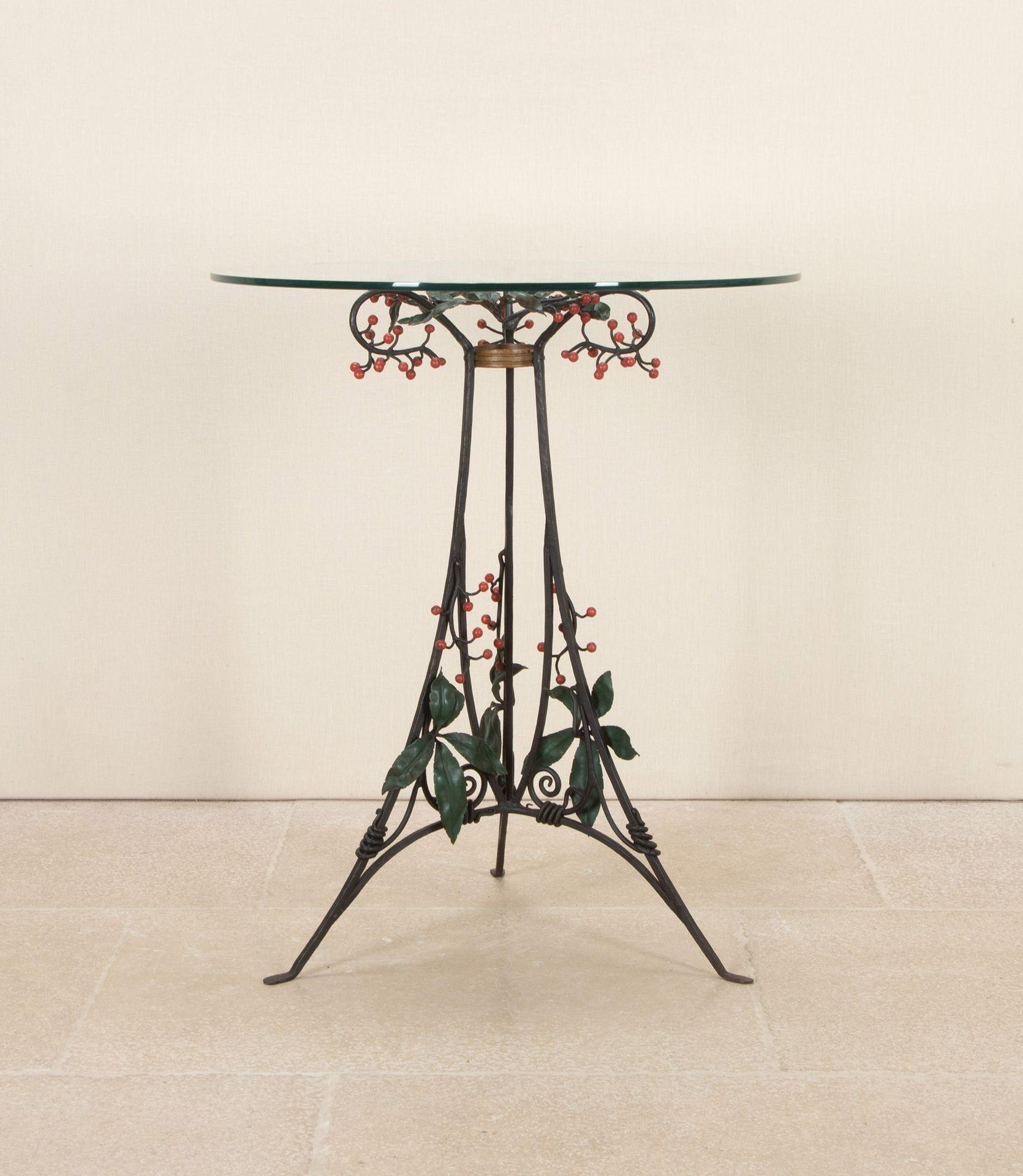 Table d'appoint Art déco italienne du 20e siècle. Circa 1930.
La base en fer forgé est décorée de feuilles et de baies peintes, sous un plateau circulaire en verre biseauté. 
La base peinte est un peu usée et la partie supérieure est légèrement