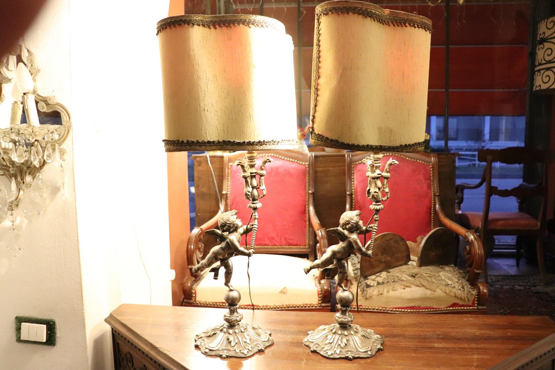 Pair of silvered bronze table lamp. The lamps are extremely refined, the forged bronze body is formed by figures of angels holding up the lamp. The lamps are working. The measures indicated are the maximum ones for the Lumen cap.