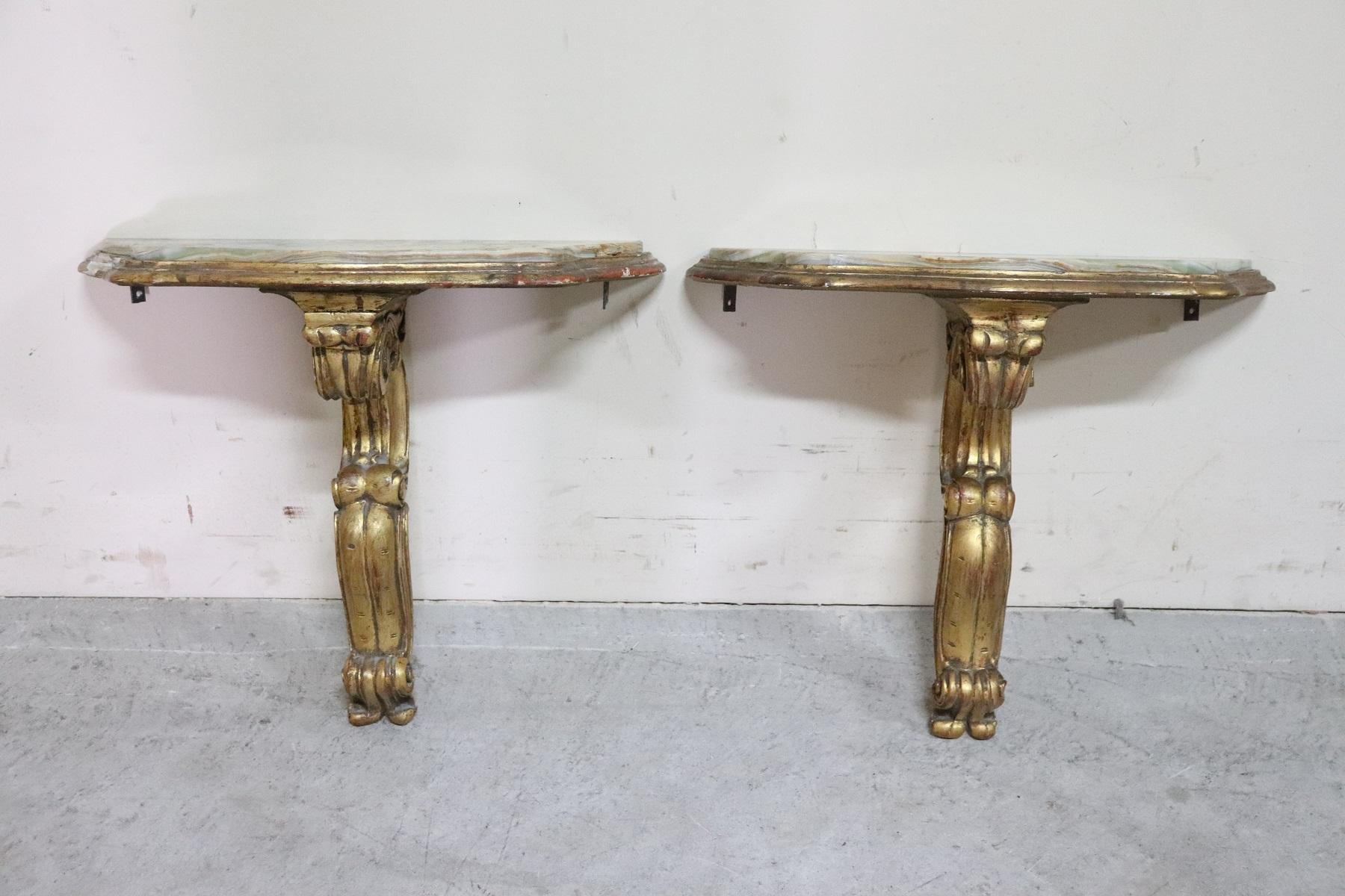Rare Italian baroque style pair of console table in carved and gilded wood. The wood is finely carved with volutes and curls. Precious decoration in gold daughter. The top is in beautiful jade color onyx. This pair of consoles is perfect to be used
