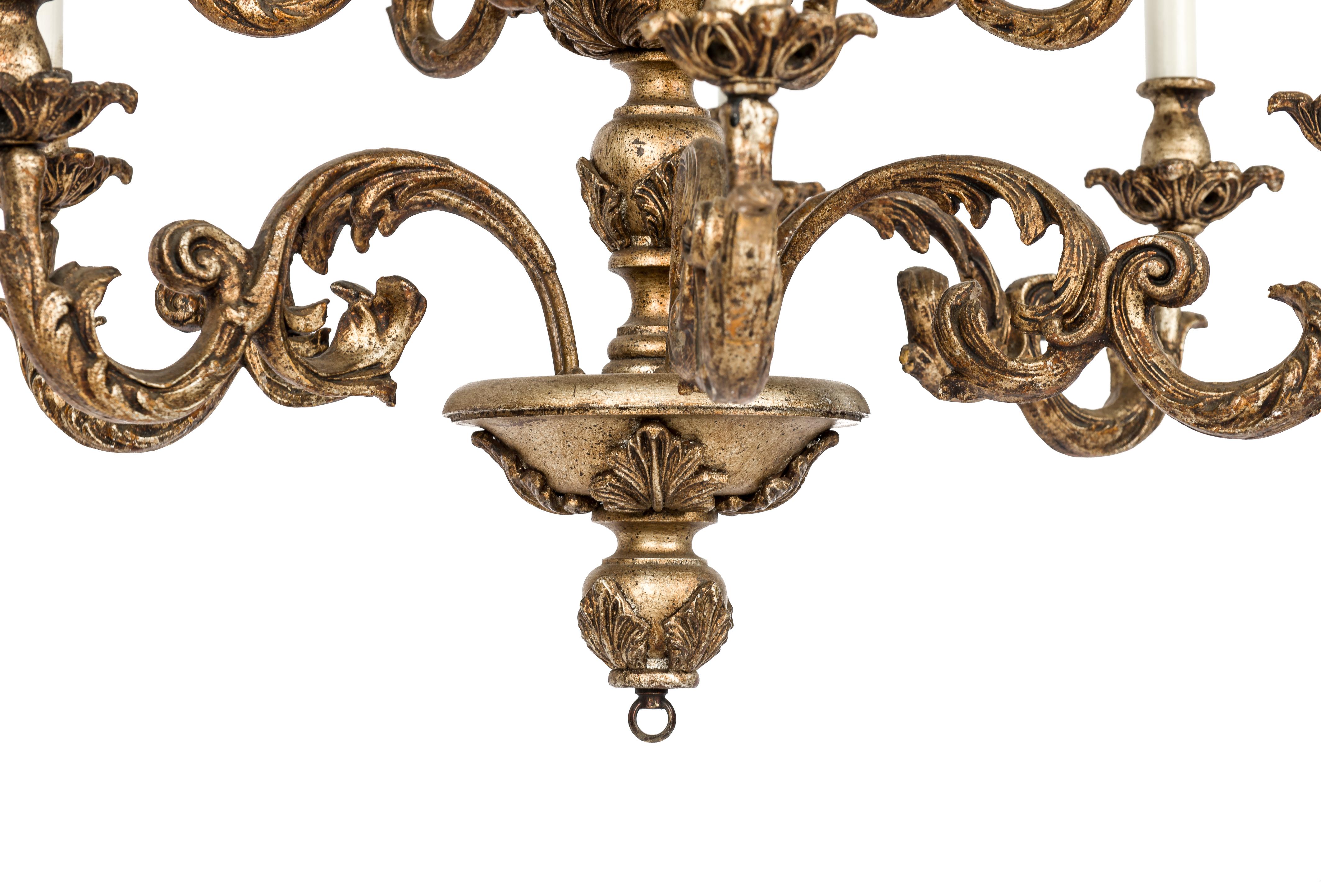 This beautiful elegant chandelier was made in Florence Italy in the early 20th century circa 1910. It features a central turned wooden column decorated with cast acanthus leaves. The chandelier has two tiers with each 6 scrolled arms ending in