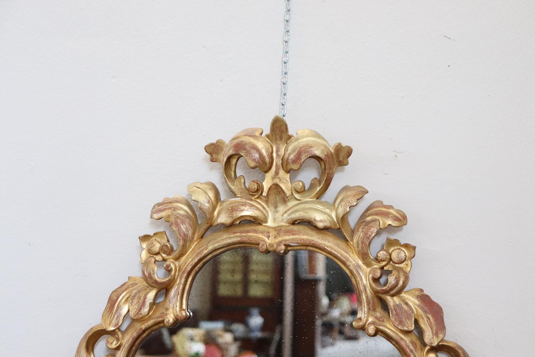 Luxury Italian Baroque style carved wood wall mirror with candleholders 1950s. Refined decoration in gilded wood. Very rich work in baroque style with curls and swirls. This mirror is perfect for a refined and elegant home.
 