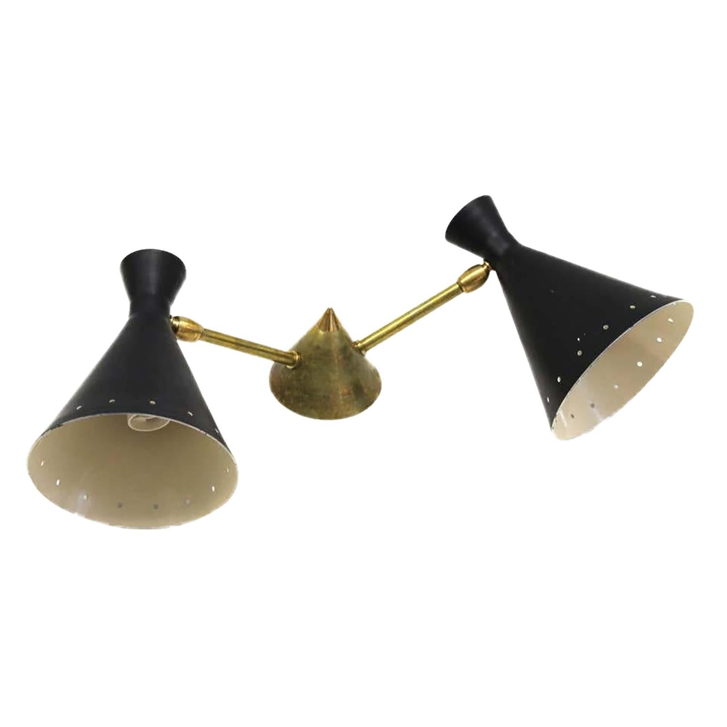 A vintage Mid-Century Modern Italian double-arm wall applique, sconce made of hand crafted metal and brass, in the style of Stilnovo in good condition. The two conical mount, perforated black lacquered metal shades of the wall are supported by