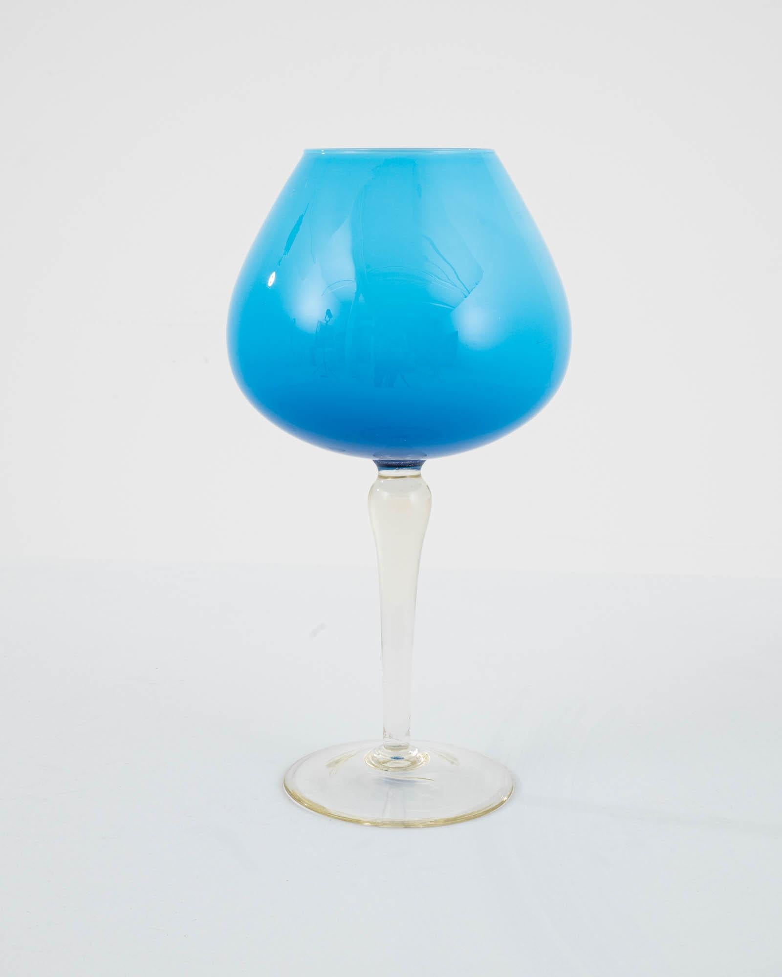 Exuding sophistication, this 20th-century Italian blue glass goblet presents a medium blue hue, elegantly crafted to evoke a sense of refined opulence. The goblet boasts a distinctive design, featuring a gracefully wide cup perched atop a pristine