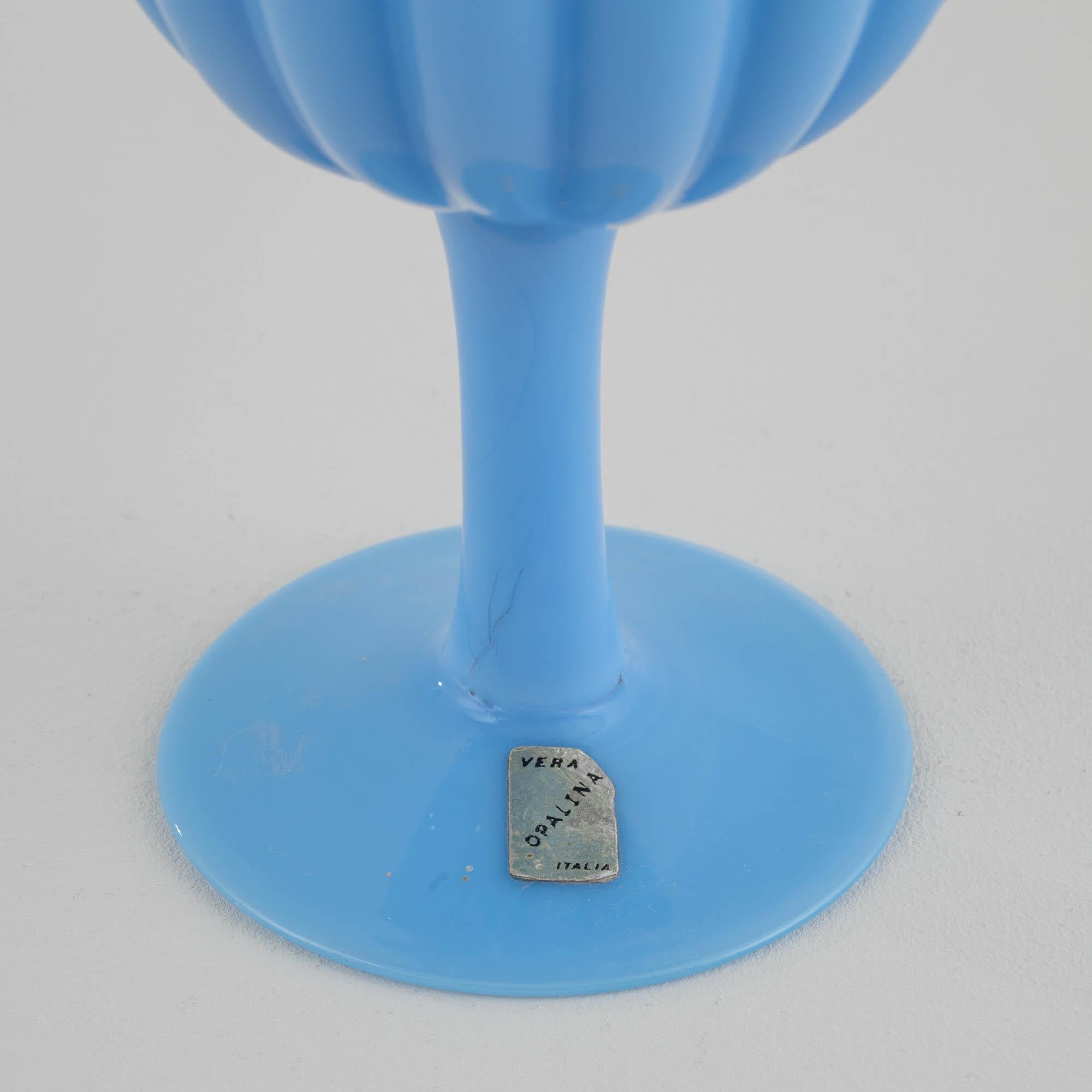 Indulge in the allure of this 20th-century Italian blue glass goblet, bathed in a mesmerizing blue ivy hue with a subtle, enchanting purple undertone. The exquisite design of the cup, adorned with graceful vertical lines, adds an element of timeless
