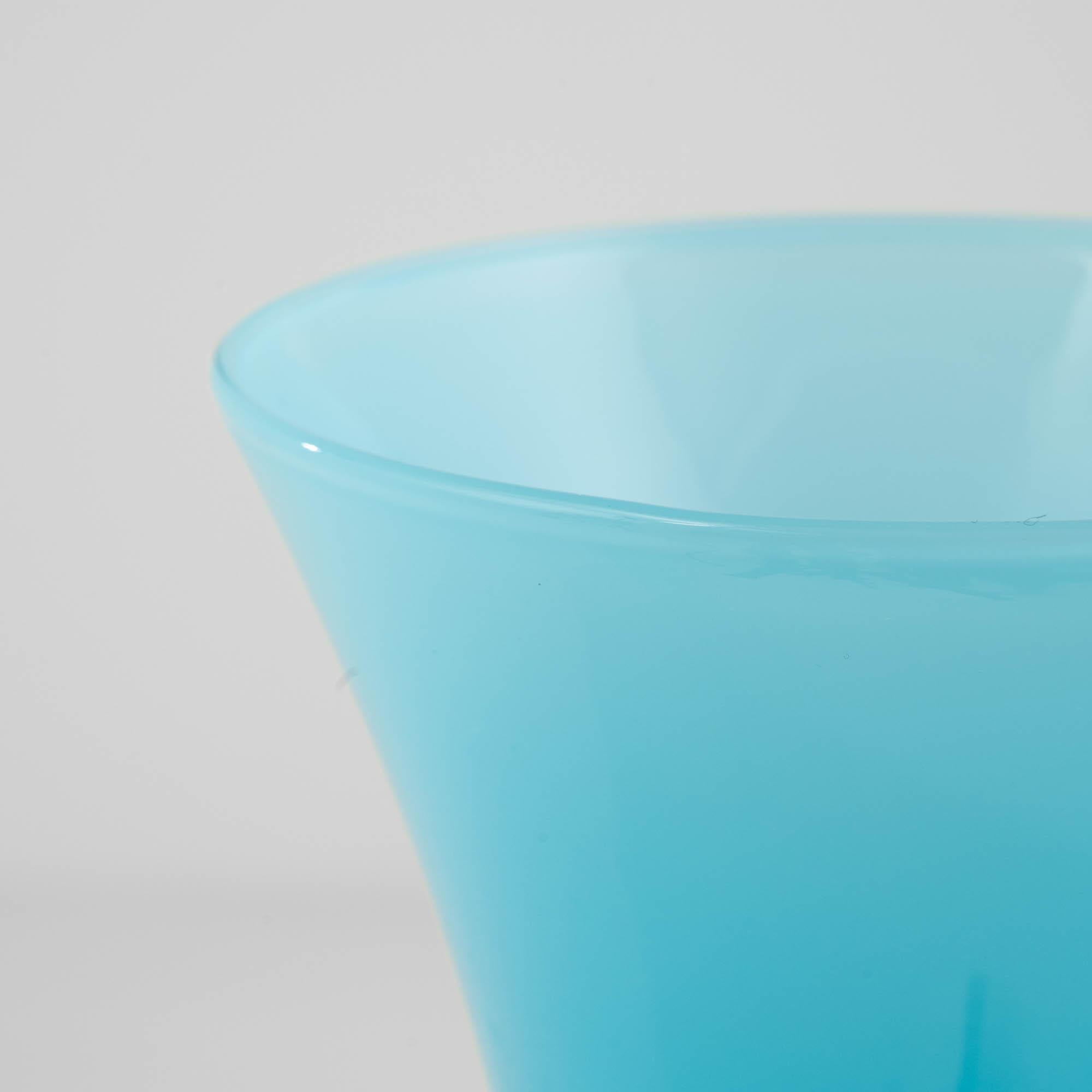 Behold the allure of this 20th Century Italian Blue Glass Goblet, a masterpiece in opaline craftsmanship. The goblet boasts a white base that serves as the perfect pedestal for its enchanting ice blue cup. A subtle gradient, transitioning from a