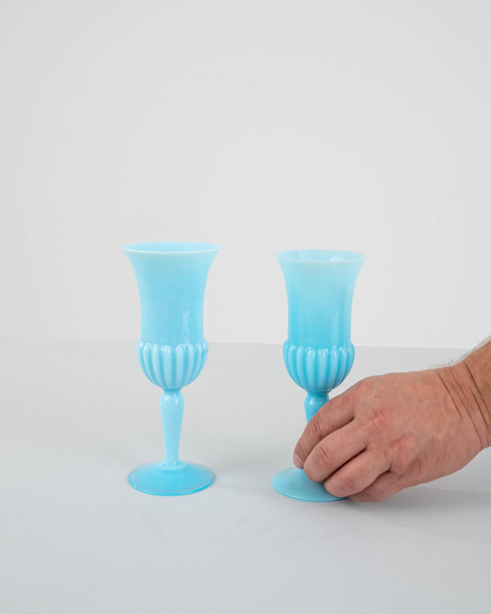 Exquisite in design, this set of two 20th-century Italian blue glass vases is a testament to elegance. The enchanting ice blue hue captivates the eye, creating a soothing and timeless aesthetic. The vases gracefully flare outward at the top, adding