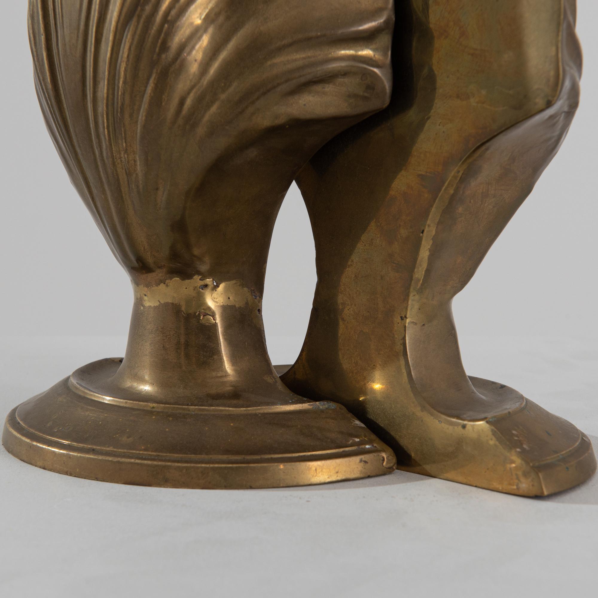 A pair of 20th century brass bookends from Italy, these gilded decorations embody an oyster-like motif, holding pearls of knowledge. Presenting a smooth surface and a molded one, these standing shells can be reunited to form a whole. The molded form