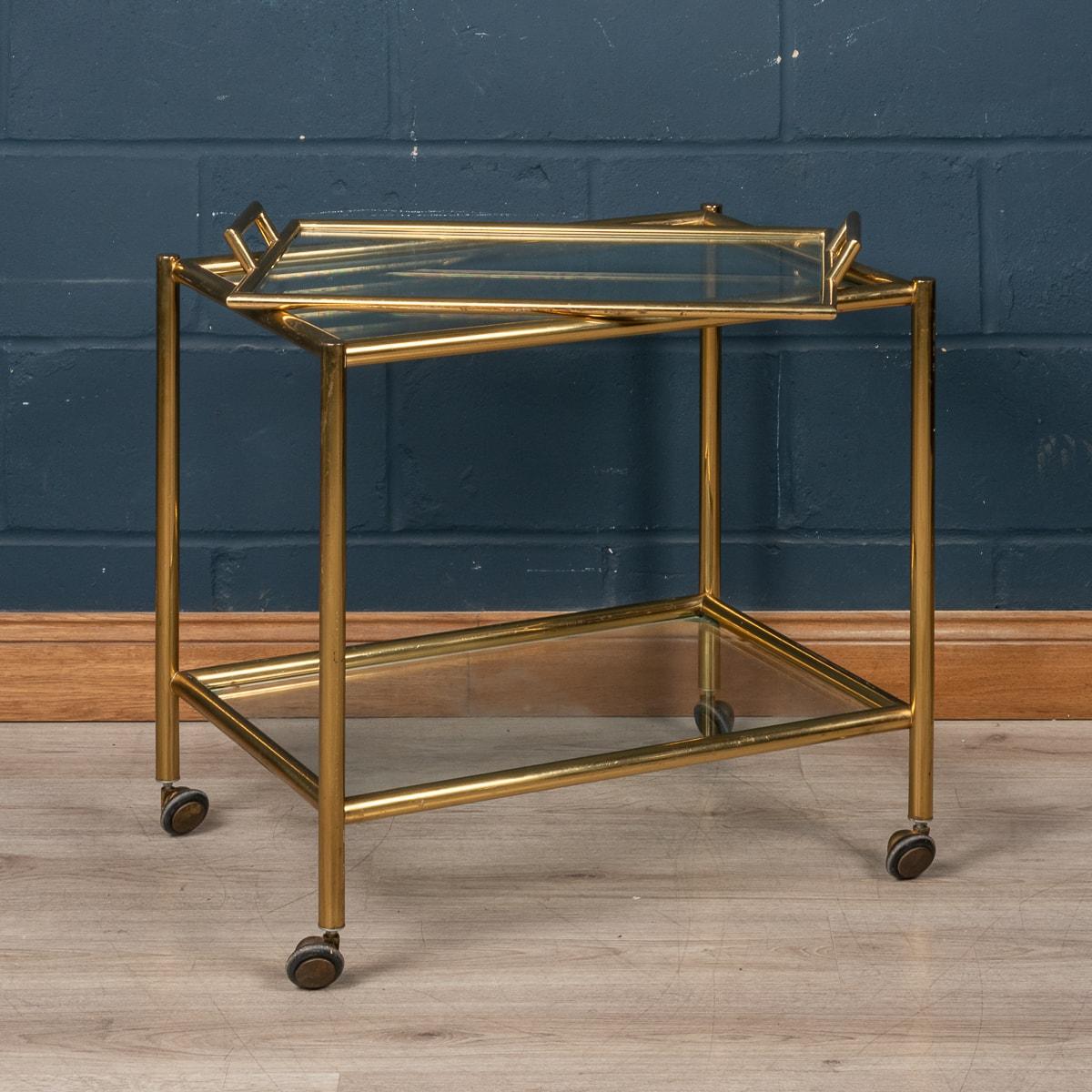 A mid to late 20th century brass effect two tier drinks trolley having a circular brass frame with removable glass tray top. This contemporary designer drinks or cocktail trolley was made in Italy in the second half of the last century and has an