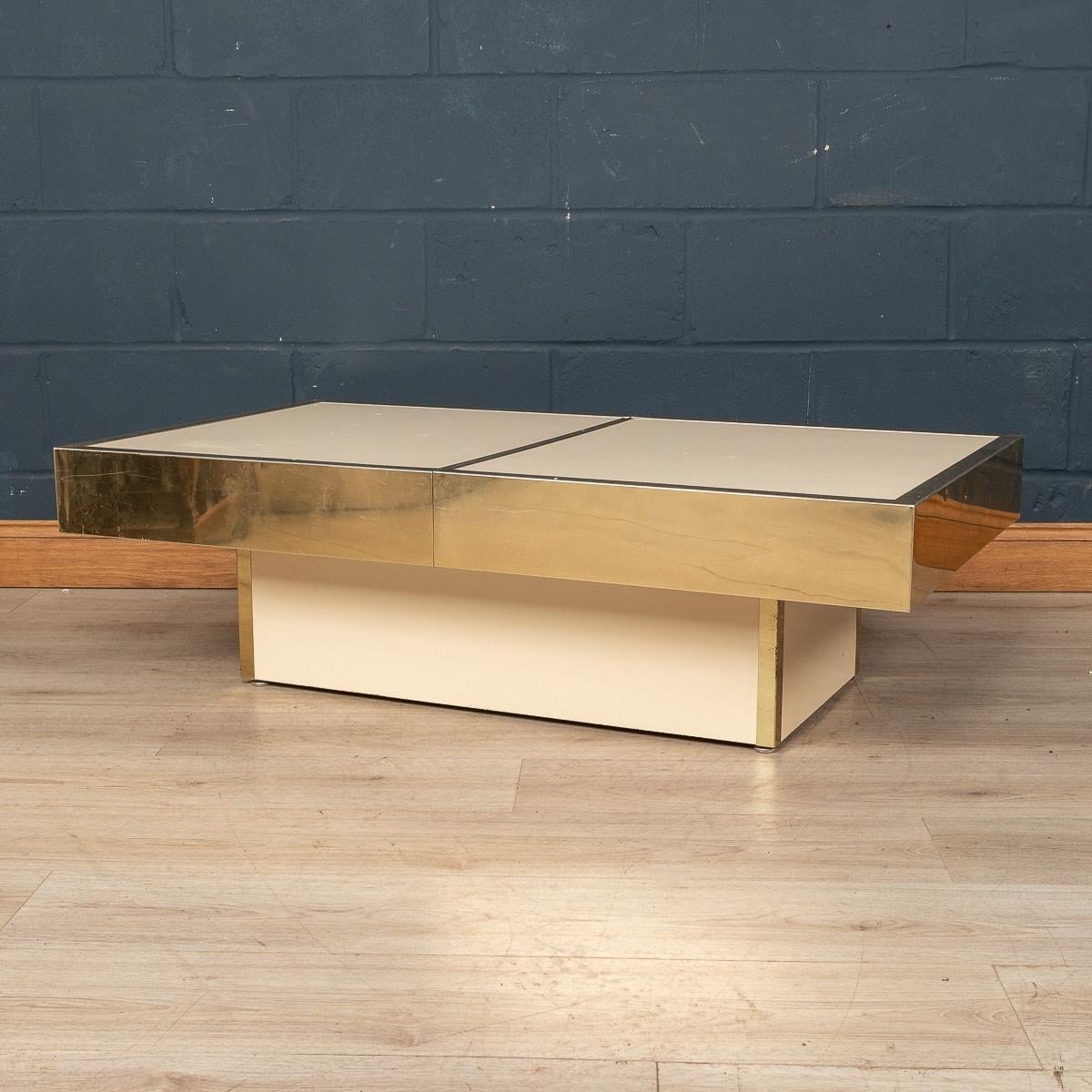 A beautiful “hidden bar” coffee table, made in Italy in the 1970s. This very well crafted coffee table is finished in cream melamine with a gilded metal blades. The top level slides apart in the middle to reveal a useful storage space for glasses