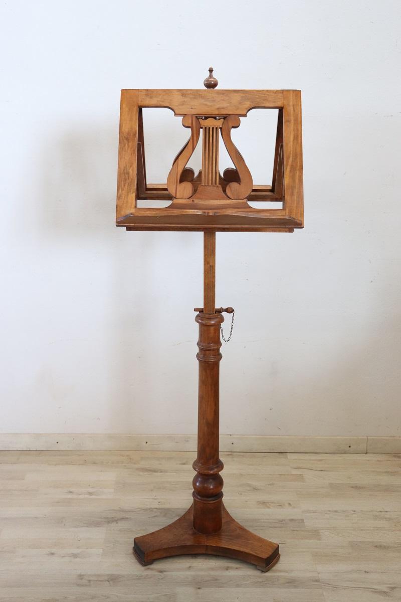 Beautiful music stand in solid carved walnut made in the 1990s. Characterized by a finely turned rod adjustable in height. The lyre-like workmanship carved into the wood on both support bases for the sheets is of great value. This beautiful music
