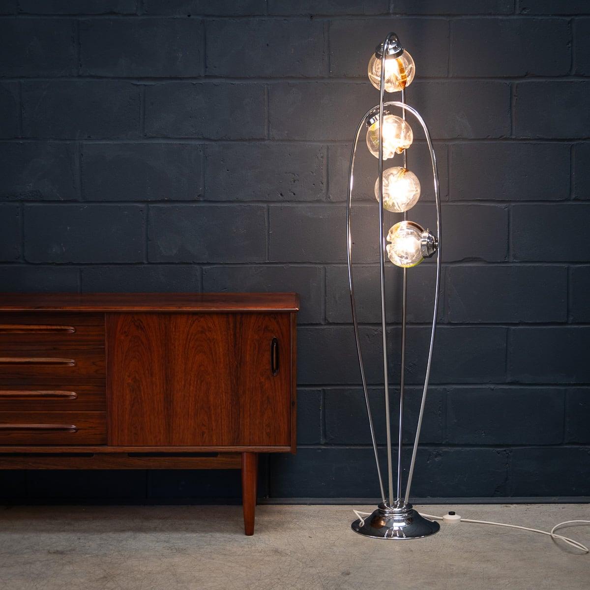 An unusual vintage Italian floor lamp with three lights attributable to Carlo Nason. Two beautiful looped structures support four hand blown Murano glass shades made by Mazzega, dating to the 1970s. Each diffuser is hand crafted in clear glass with