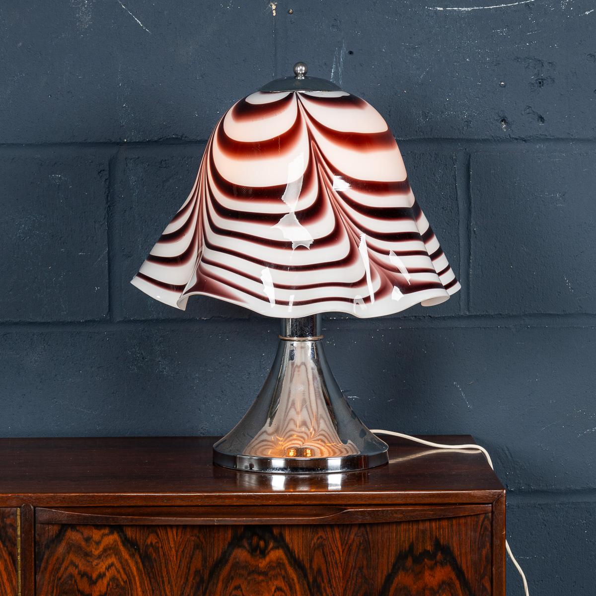 Introducing an exquisitely crafted chrome and glass table lamp originating from Italy during the mid-20th century. The chrome stand serves as a graceful support for a handcrafted glass 