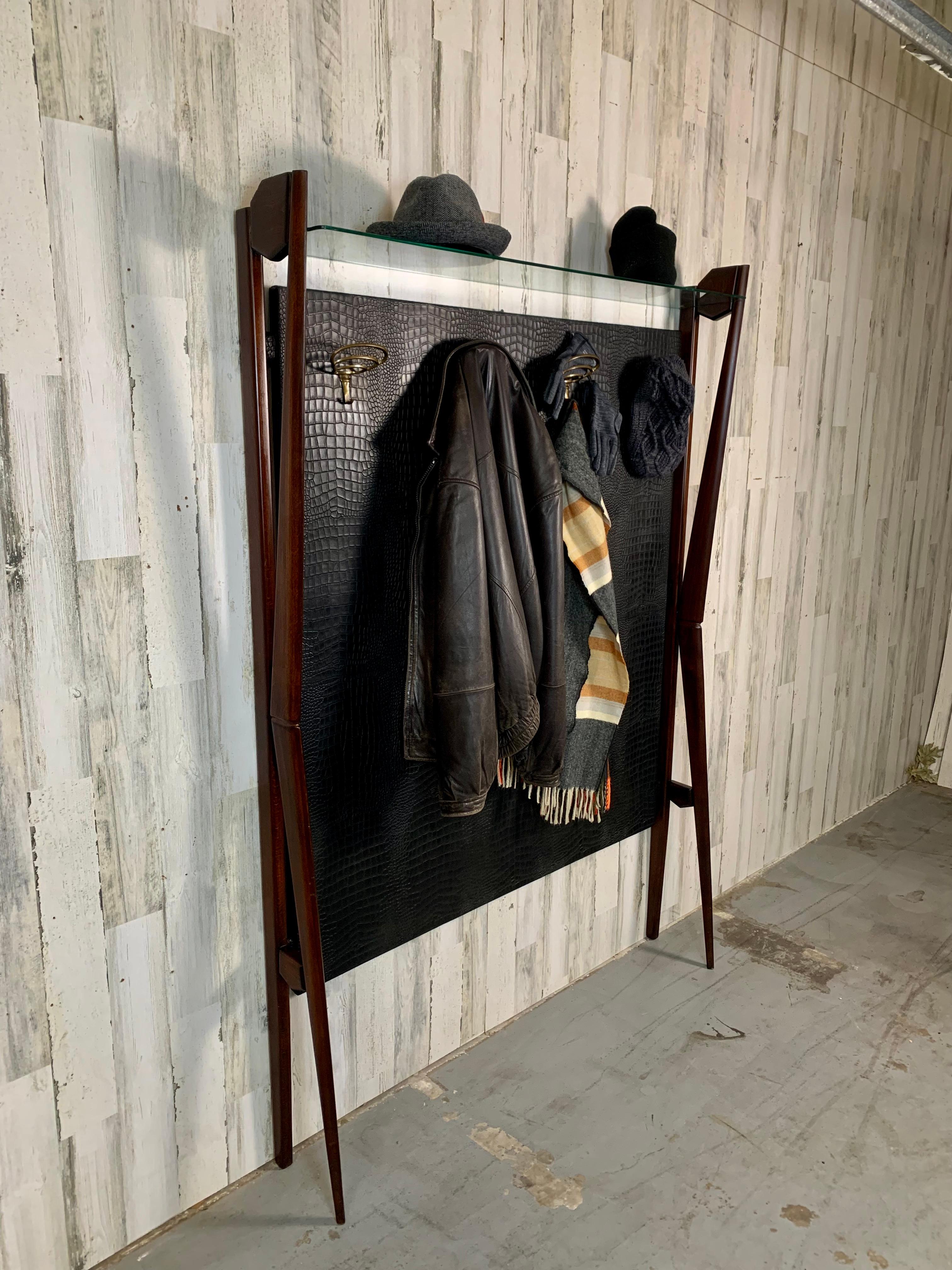 Italian design hall tree with a glass shelf for your hat over mahogany stained hardwood compass legs and faux black crocodile leather
with brass hooks for hanging coats.