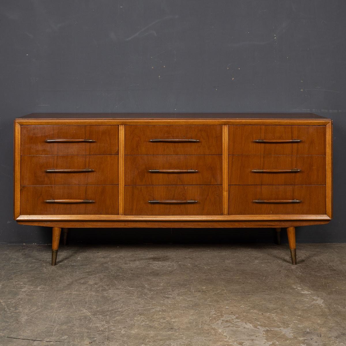 An Italian-made wooden credenza from the captivating mid-20th Century era. This distinguished piece features a total of nine drawers adorned with timeless, atomic-style brass-tipped handles, all elegantly supported by four legs accented with brass