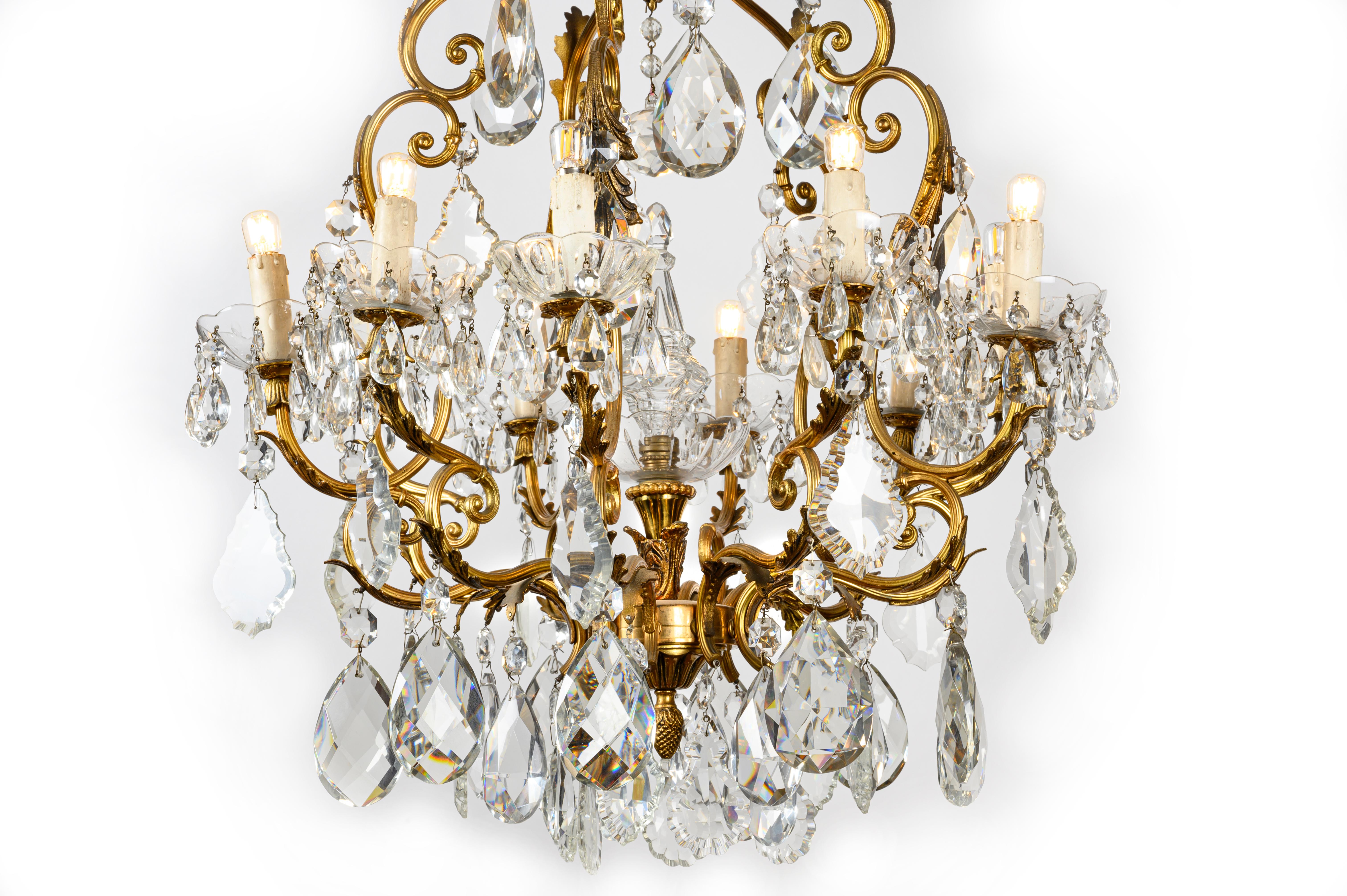 A romantic crystal and gilt bronze chandelier of Italian origin, a ten-light pendant dating back to the mid-20th century, with a beautiful birdcage shaped frame, adorned with cast gilt bronze foliate elements.
The base of the piece features a