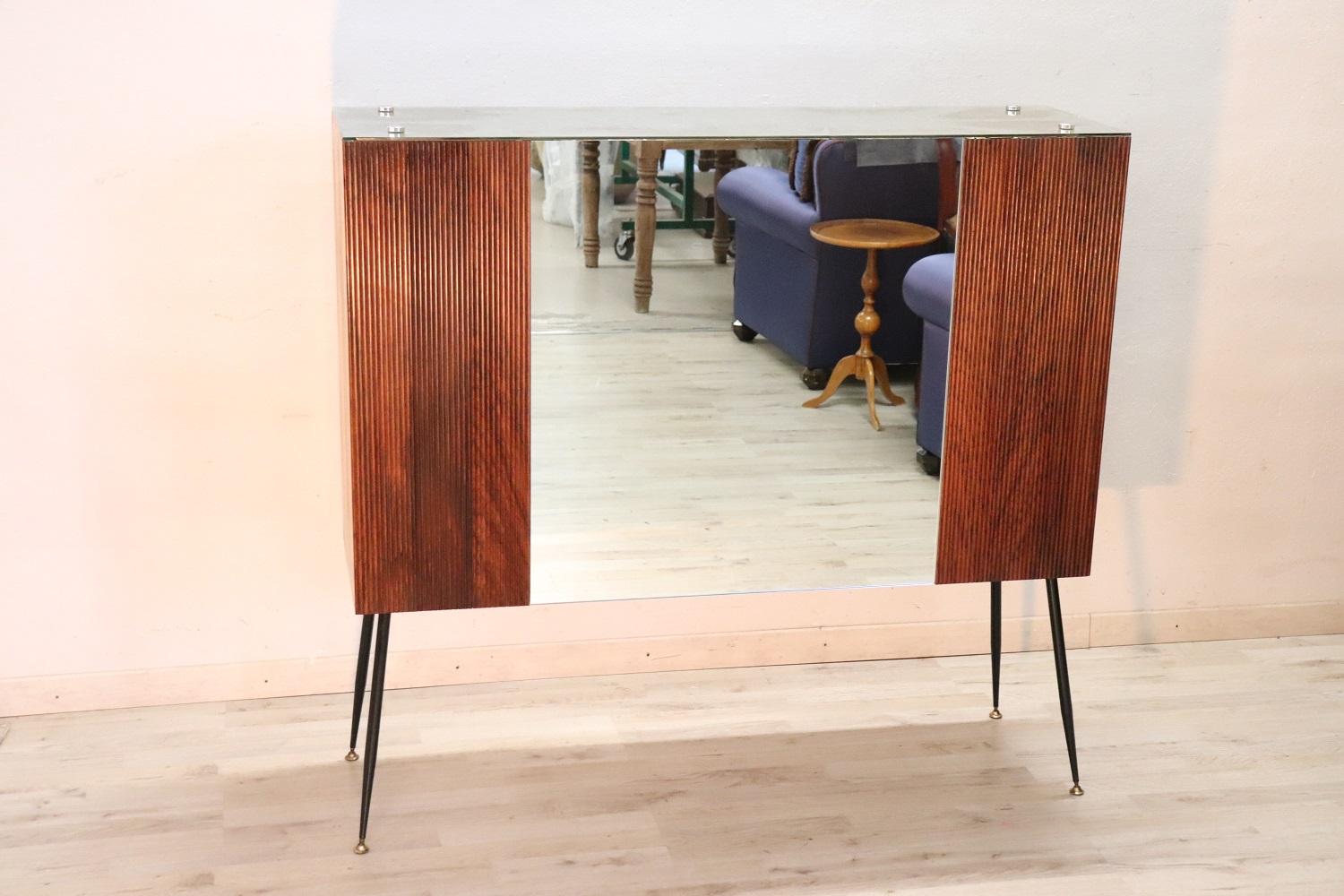 Beautiful and rare Italian design bar cabinet 1960s. Made of fine wood. This rare bar cabinet was made to be placed in the center of the room. On the front it is only decorative with a large central mirror, on the back it is equipped with many