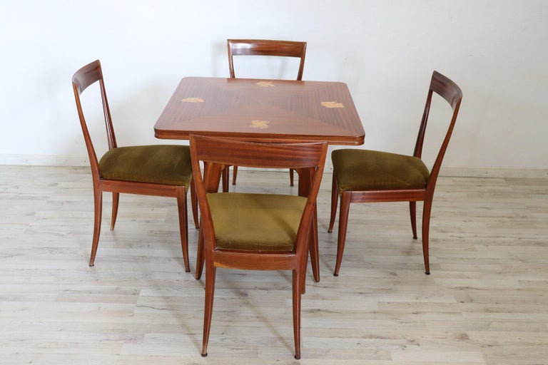 Italian design table with four chairs, 1940s in mahogany wood. Very linear and essential in the style of Ico Parisi in precious mahogany wood. The tabletop presents refined decoration with inlaid designs in the corners. The chairs have a green