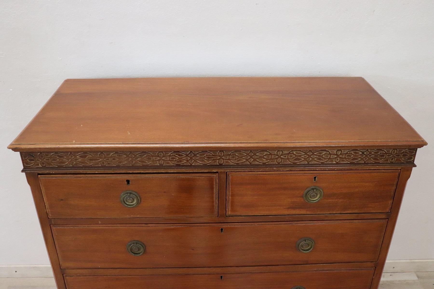 Italian chest of drawers 1950s in mahogany wood. Very linear and essential with five comfortable drawers. Refined decorative frame under the top carved in the wood. The handles are in finely chiseled bronze It shows signs of wear at the finishing