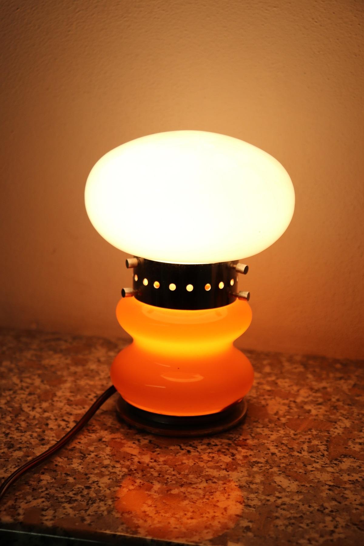Italian design table lamp by Mazzega, 1970s, with one light. The body is in chrome and precious Murano glass in orange color. Perfect for your bedside table or your desk. Very elegant, for vintage environments. This article is for you at an