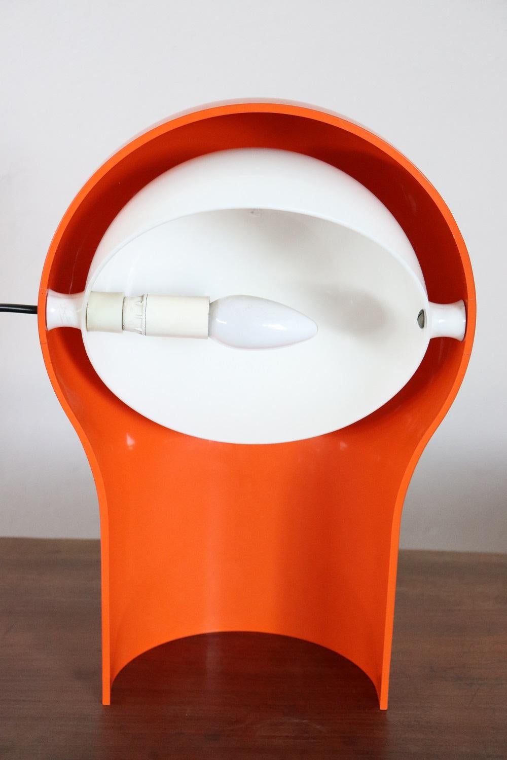 Italian design table lamp by Vico Magistretti for Artemide, 1960s, with one light. The body is in plastic orange color and the shade is white color. Shade adjusts up and down. Perfect for your bedside table or your desk. Very elegant, for vintage