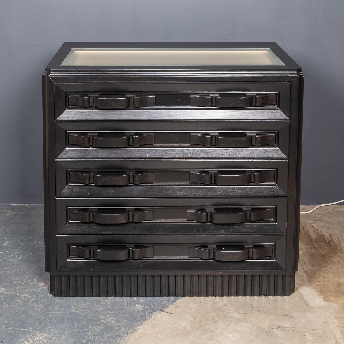 Striking 20th century Italian ebonised chest of four pull-out drawers with a lit up vitrine display top and carved buckle shaped handles and panelled sides.

Measures: Width 100cm
Height 96cm
Depth 55cm.