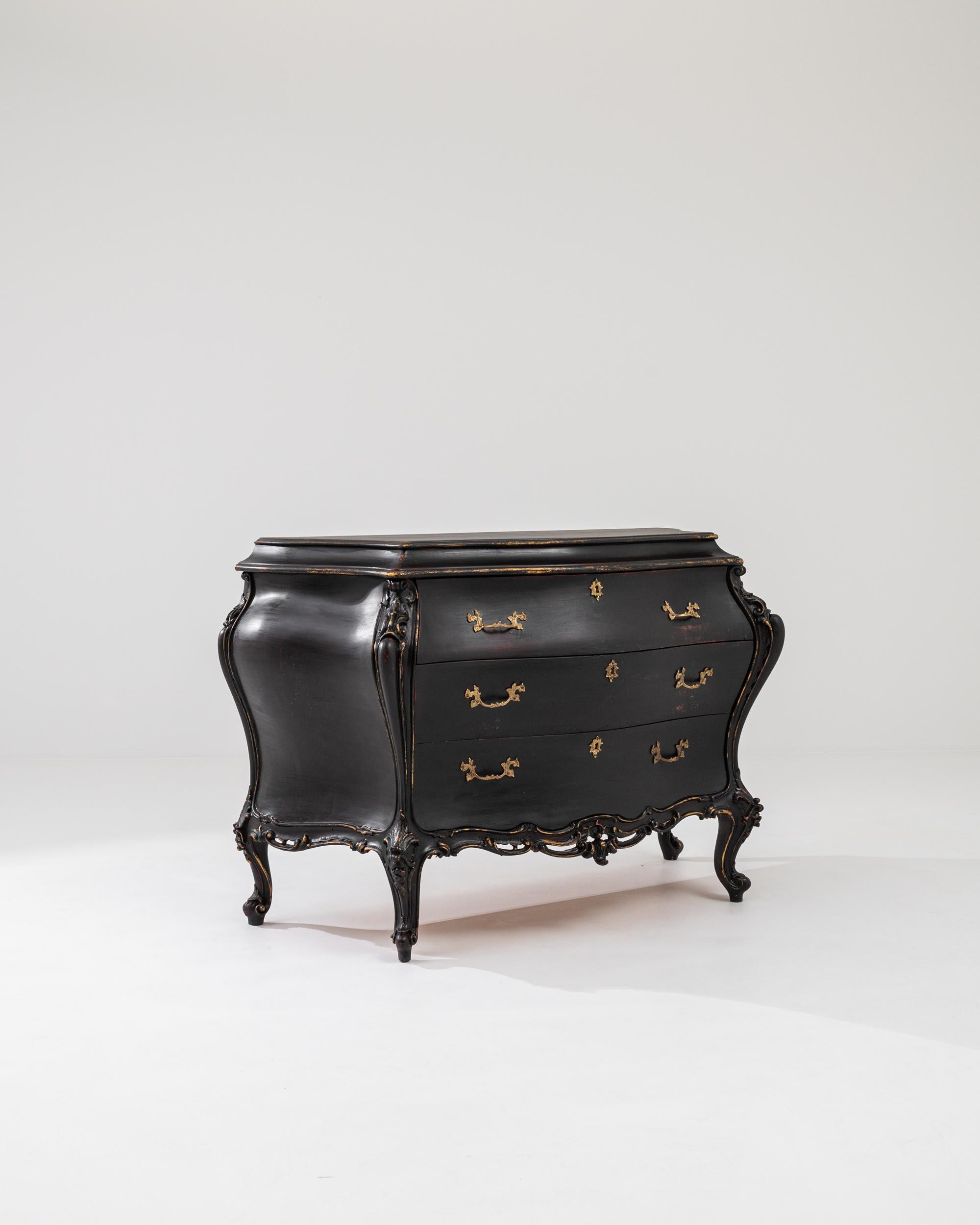 Graceful and ornate, this vintage wooden chest of drawers offers a Rococo fantasy in a somber ebonized finish. Made in Italy in the 20th century, the design takes inspiration from the ostentatious furniture of the Baroque period: the serpentine form