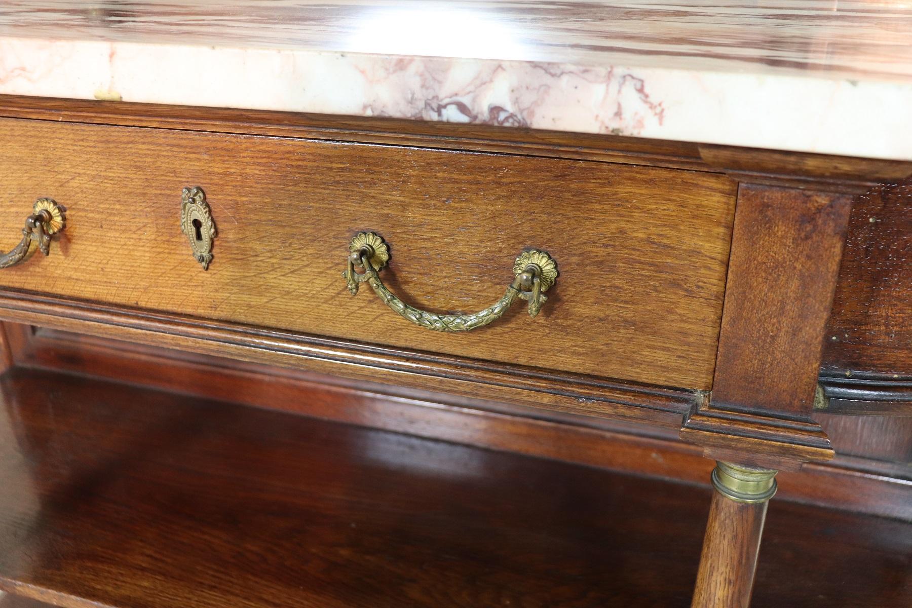 Italian antique console table, circa 1920. Characterized by precious oakwood. The console is presented in Empire style with elegant columns on the front and golden bronzes. particular round shape. A comfortable and spacious drawer on the front,