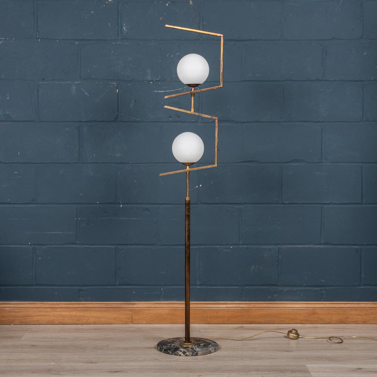 A beautiful floor lamp produced by Stilnovo, Milan, Italy. This lamp was produced in the 1960's and does not show its age at all both in terms of looks and condition. The geometric brass design holds two white opalescent diffusers, fastened to a