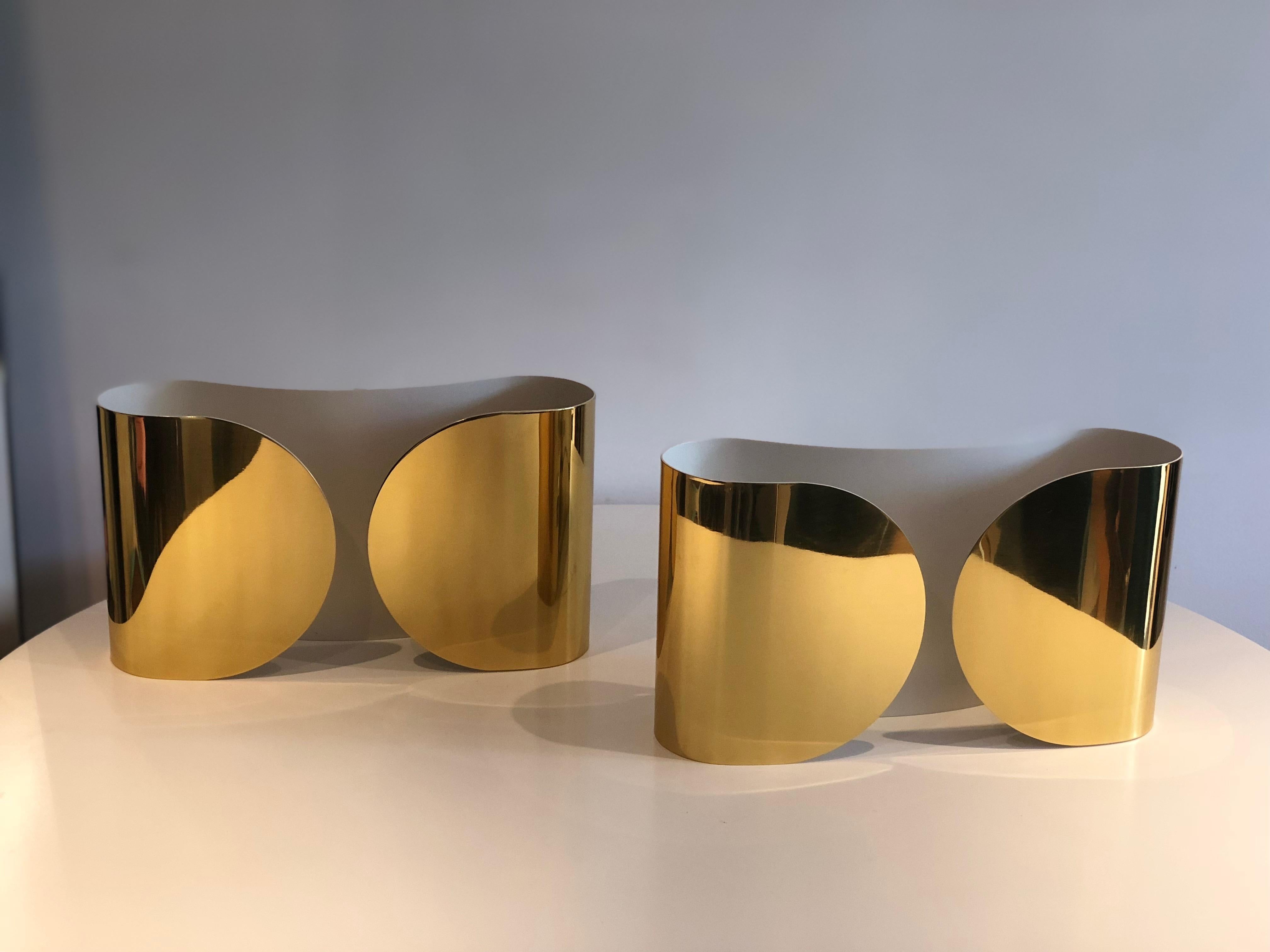 A pair of Foglio wall light sconces by Tobia Scarpa for Flos in a polished brass finish and white enamel interiors. Each curved design fits two lights and are in fully working condition. 
Each in their original boxes, plastic wrap and silver