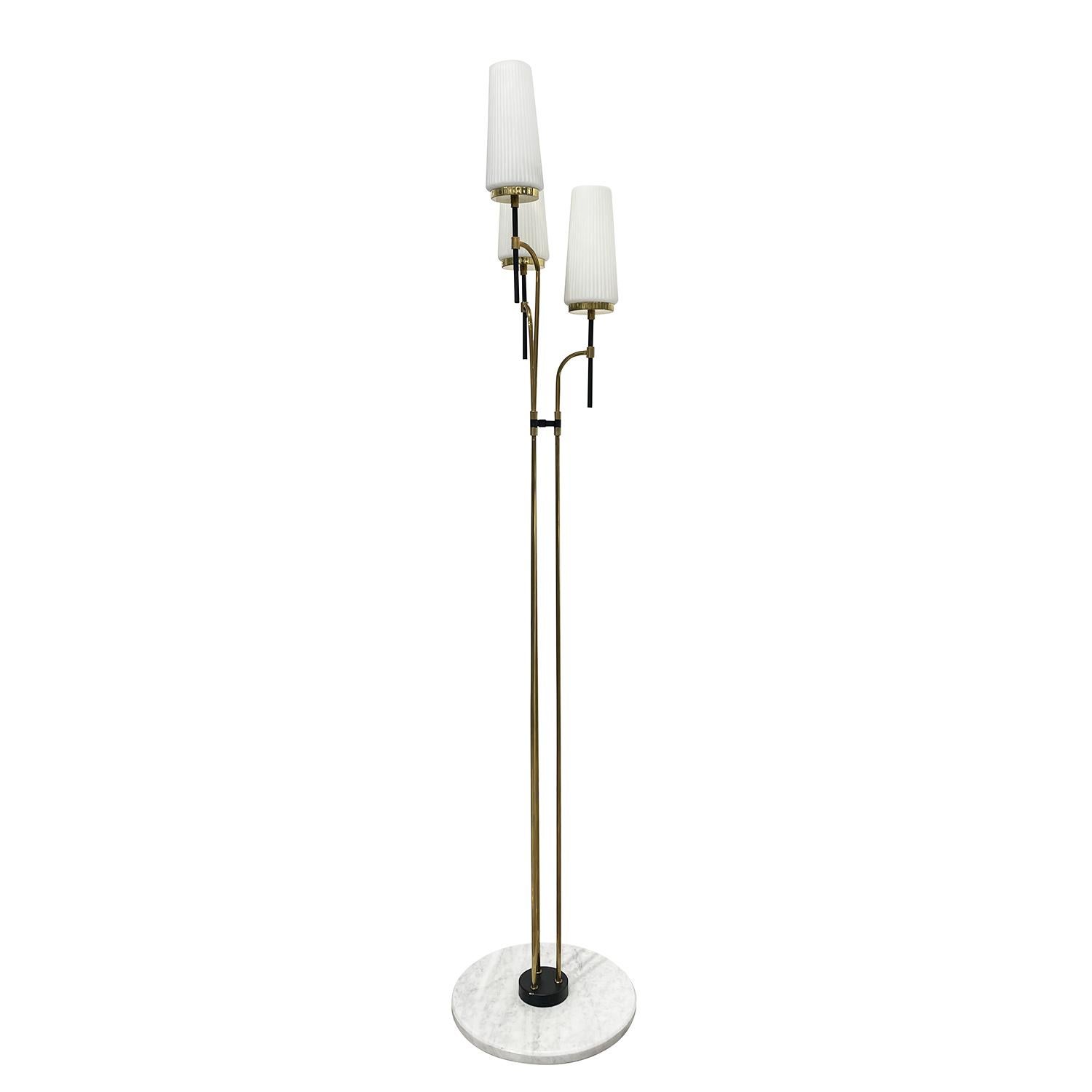 A gold, vintage Mid-Century Modern Italian floor lamp made of handcrafted metal and polished brass attributed to Stilnovo, in good condition. The detailed light is composed with three round cylindrical, frosted opaline glass shades, each of the