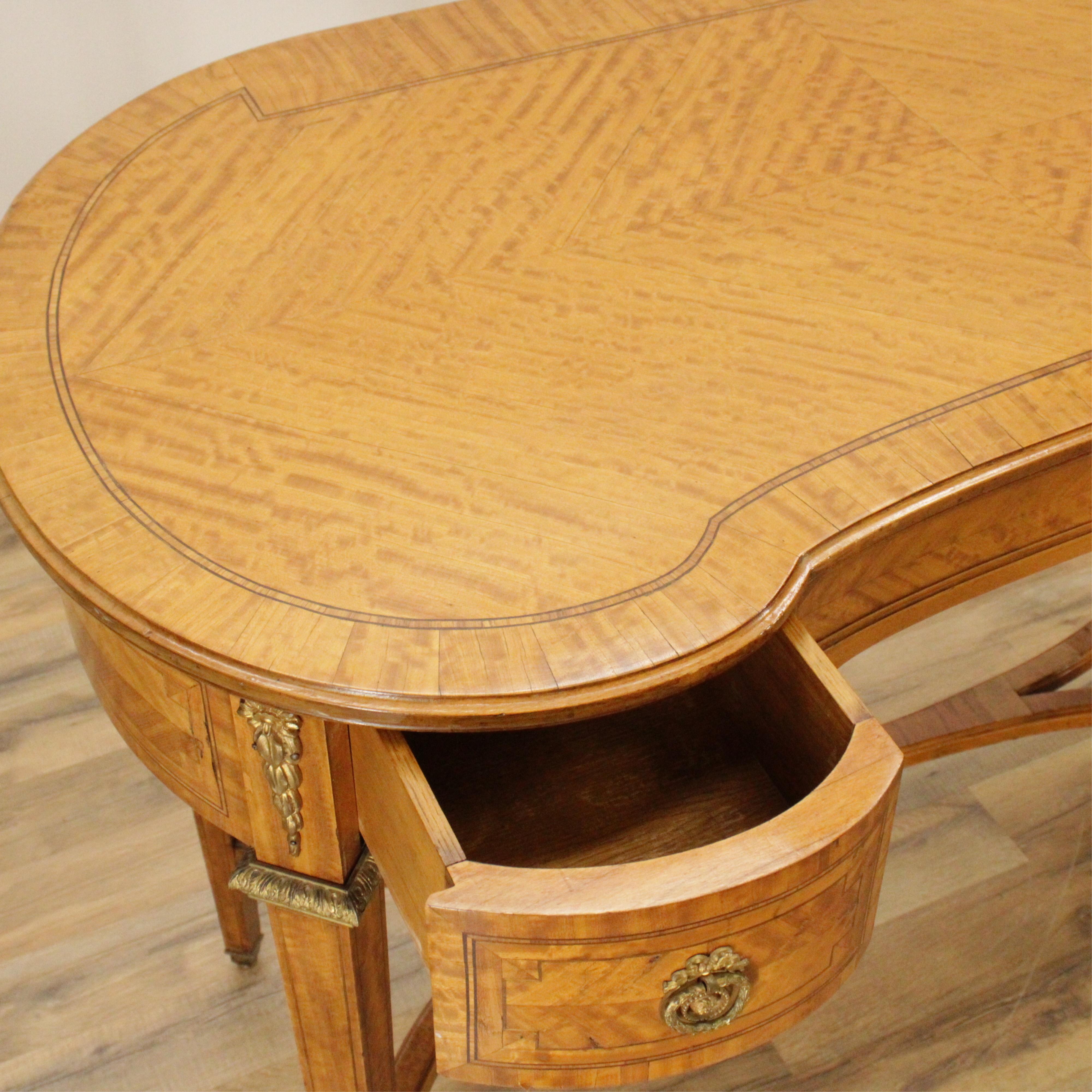 George III style satinwood dressing table or desk with kidney form, large middle drawer and two small side drawers with stretcher base. 
Measures: 30.5
